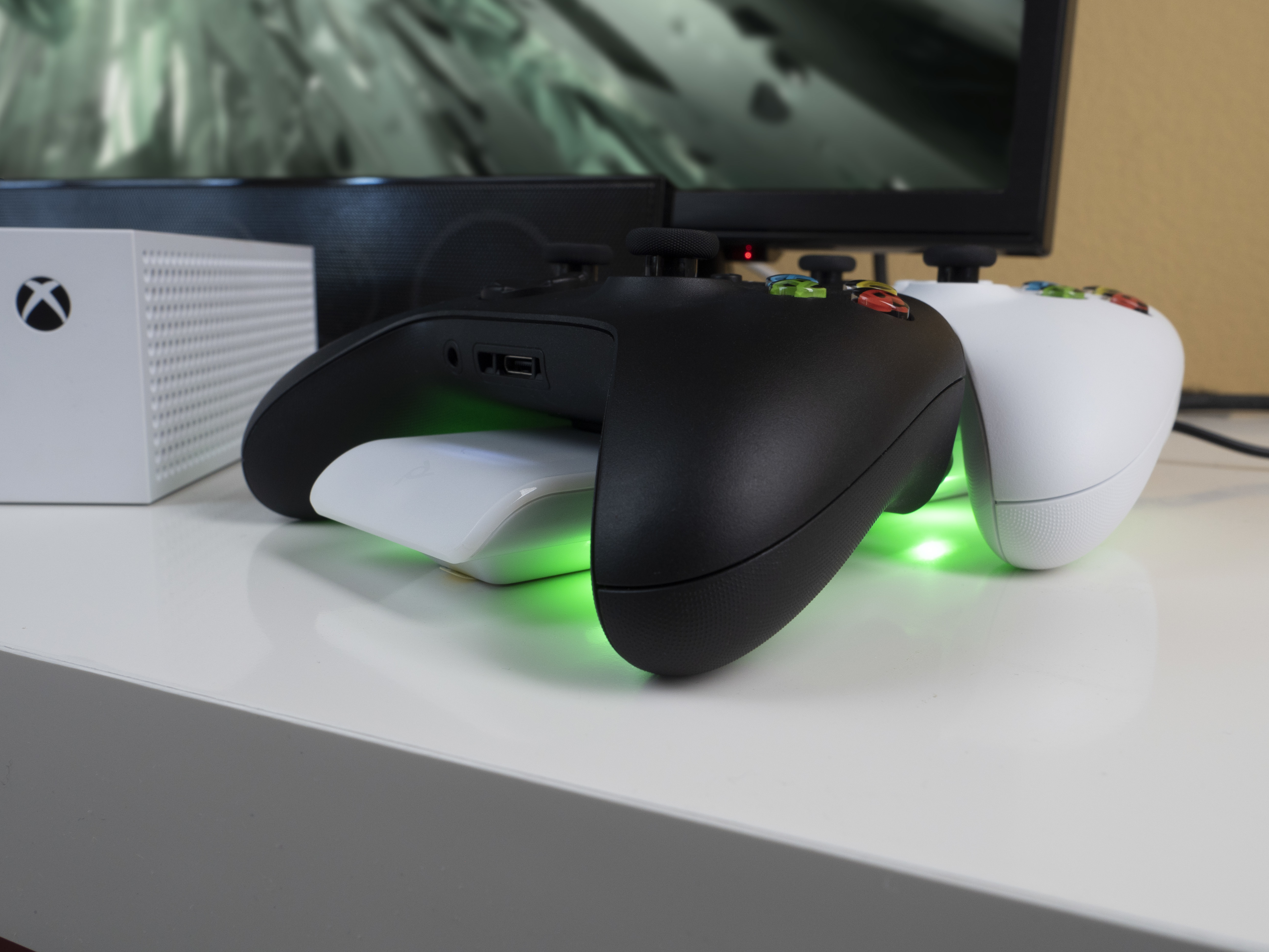 Czarne i białe kontrolery do gier na białej powierzchni z białą myszą. Konsola Xbox w tle.
