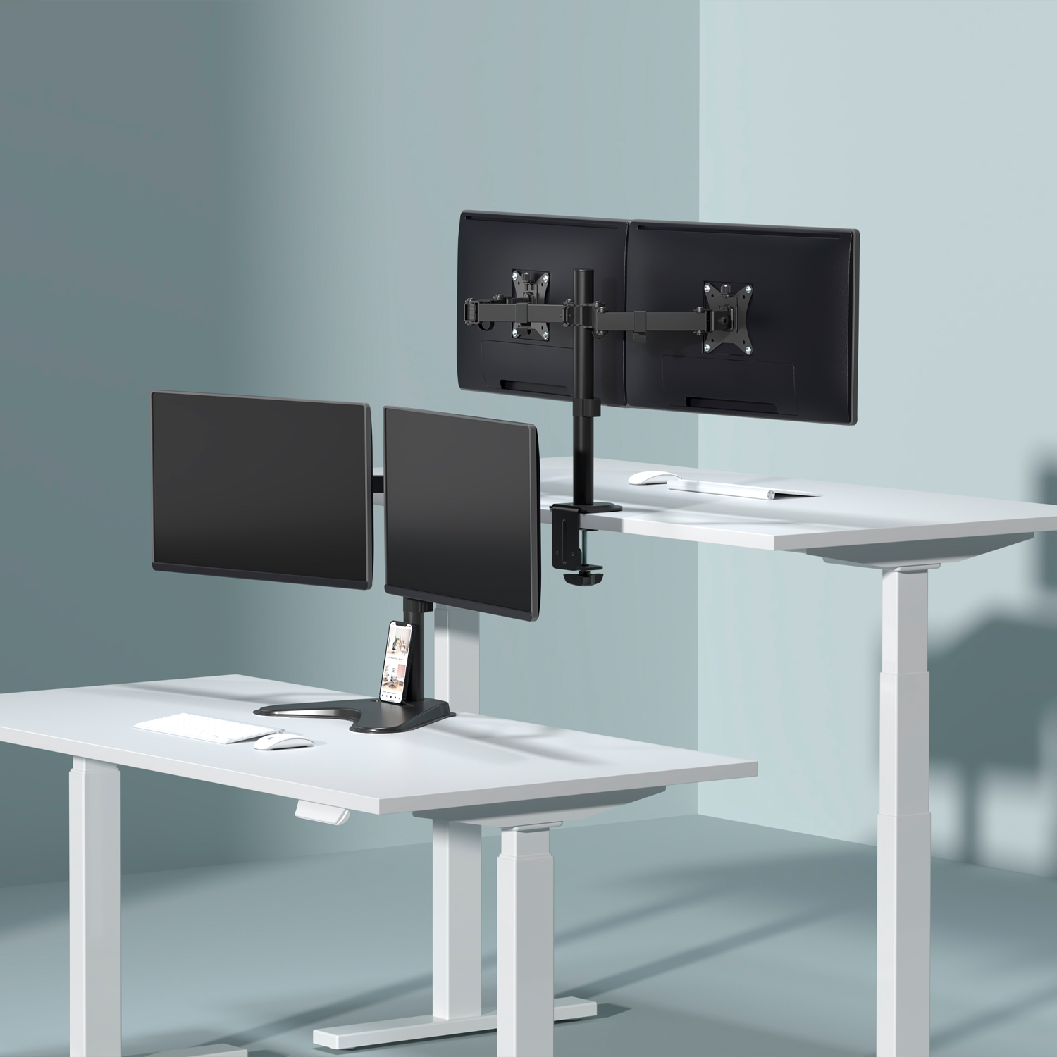 Dwa biurka z monitorami. Każde biurko ma dwa monitory. Telefon leży na biurku. Białe biurka z białymi nogami.