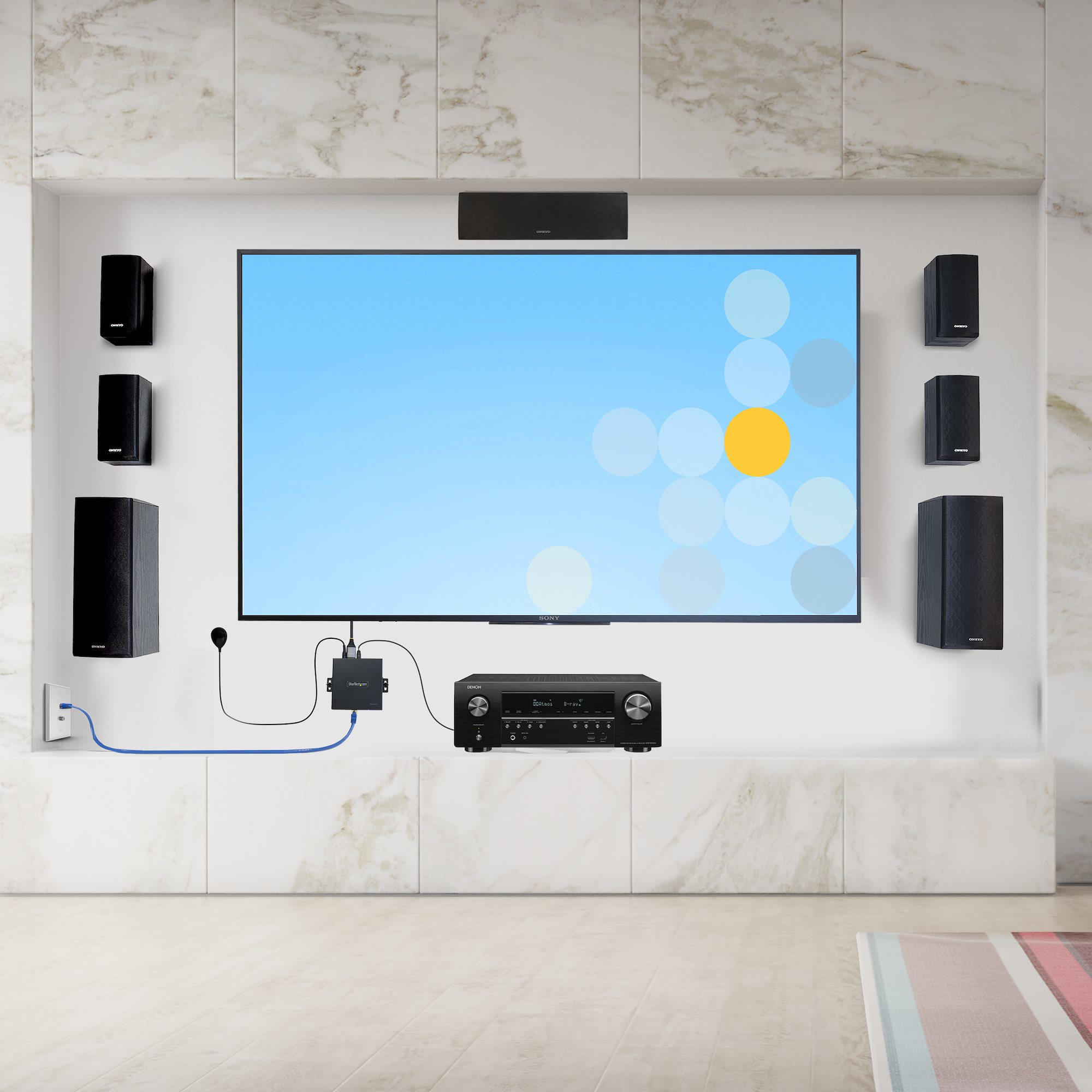 Eine moderne Heimkinoanlage mit großem Fernseher, Lautsprechern und Receiver an einer Marmorwand.