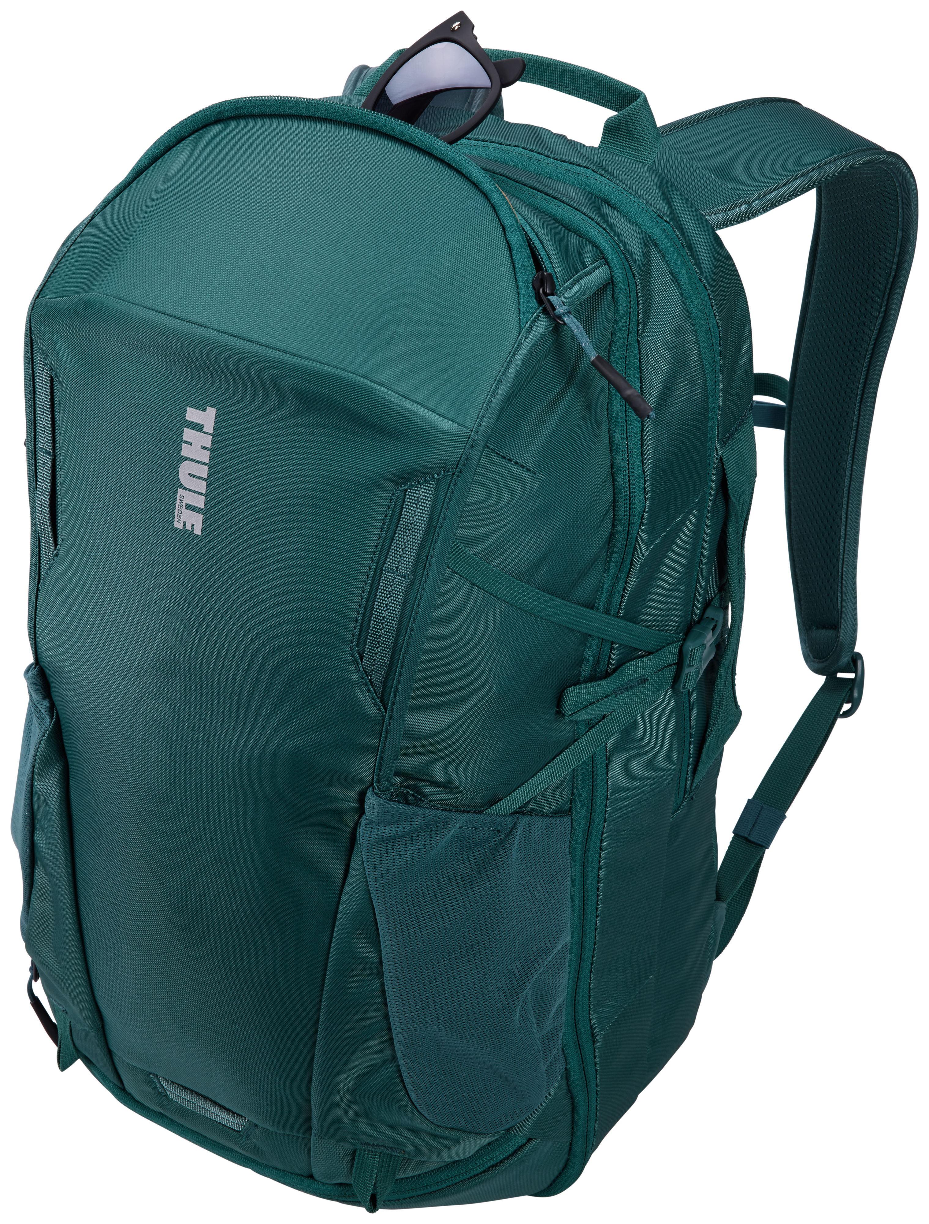 Ein grüner Rucksack mit Sonnenbrille oben. Er hat mehrere Fächer und den Markennamen 'Thule'.