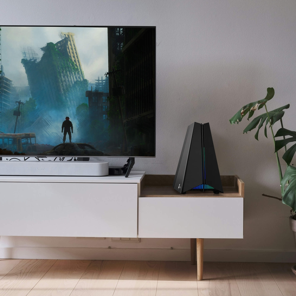 Ein modernes Wohnzimmer mit einem Fernseher, der eine postapokalyptische Szene zeigt. Ein schwarzer Computer steht auf einem weißen Schrank. Rechts ist eine Pflanze.