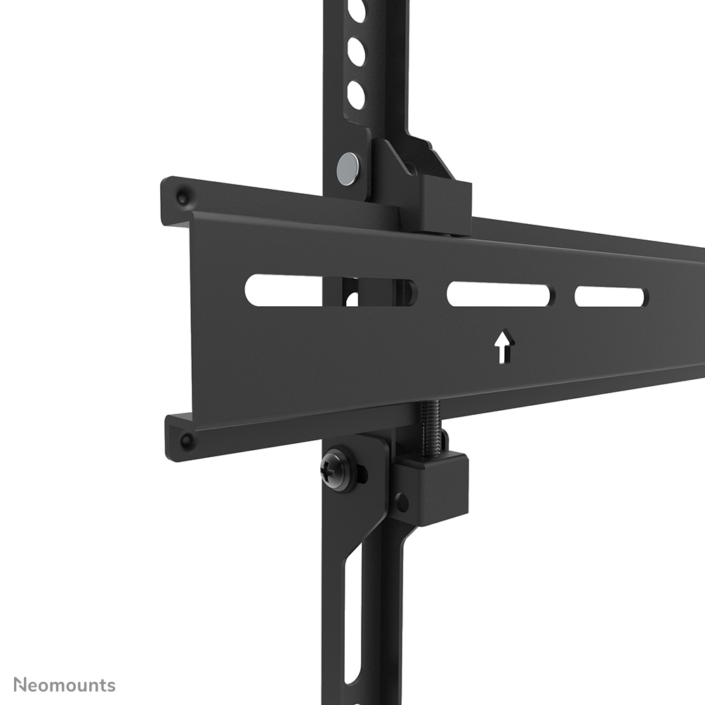 A close-up of a black TV mount. It has metal bars with holes, slots, and an upward arrow. The background is white.