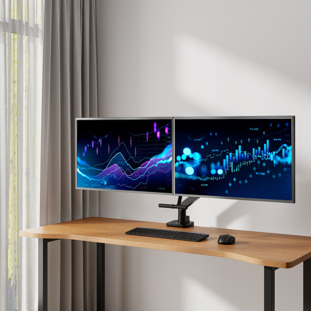 Twee monitoren met grafieken op een houten bureau. Toetsenbord en muis aanwezig. Raam aan de linkerkant.