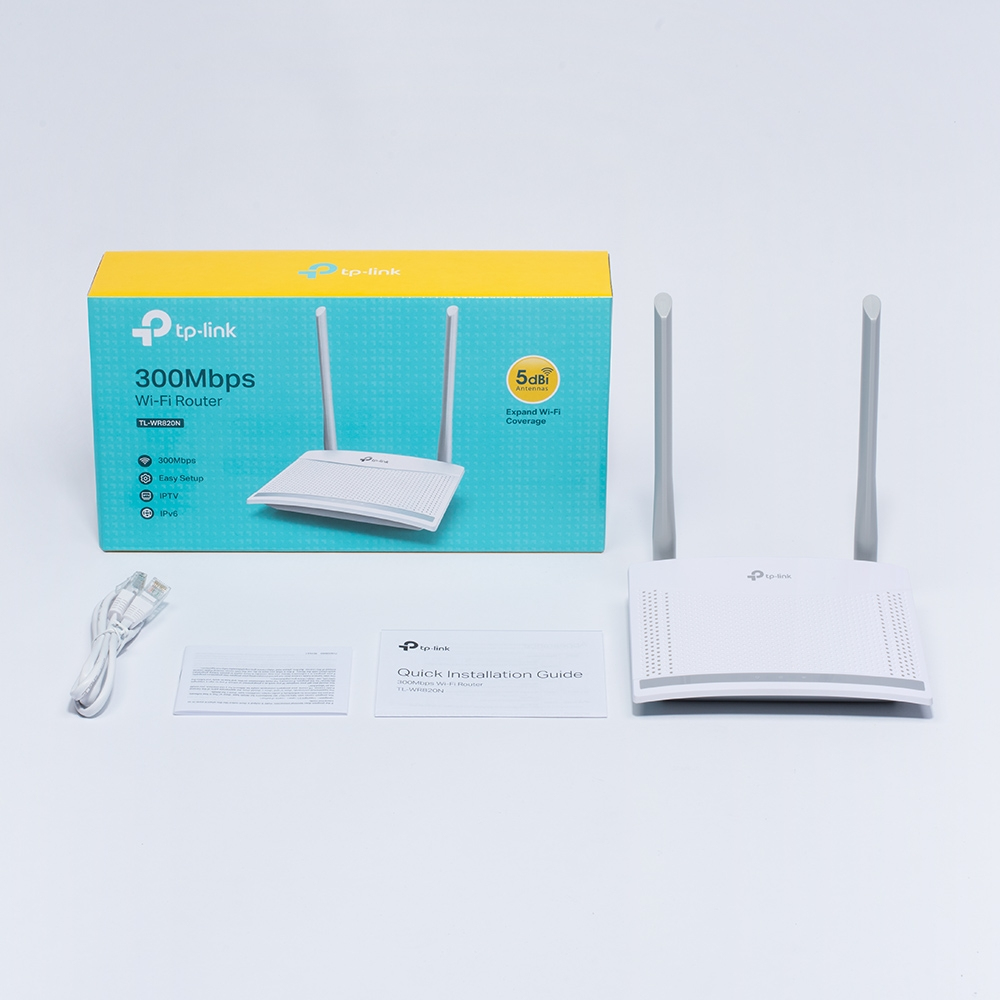 Biały router Wi-Fi TP-Link, pudełko i akcesoria na białej powierzchni. Na pudełku napis 300Mbps Wi-Fi Router.