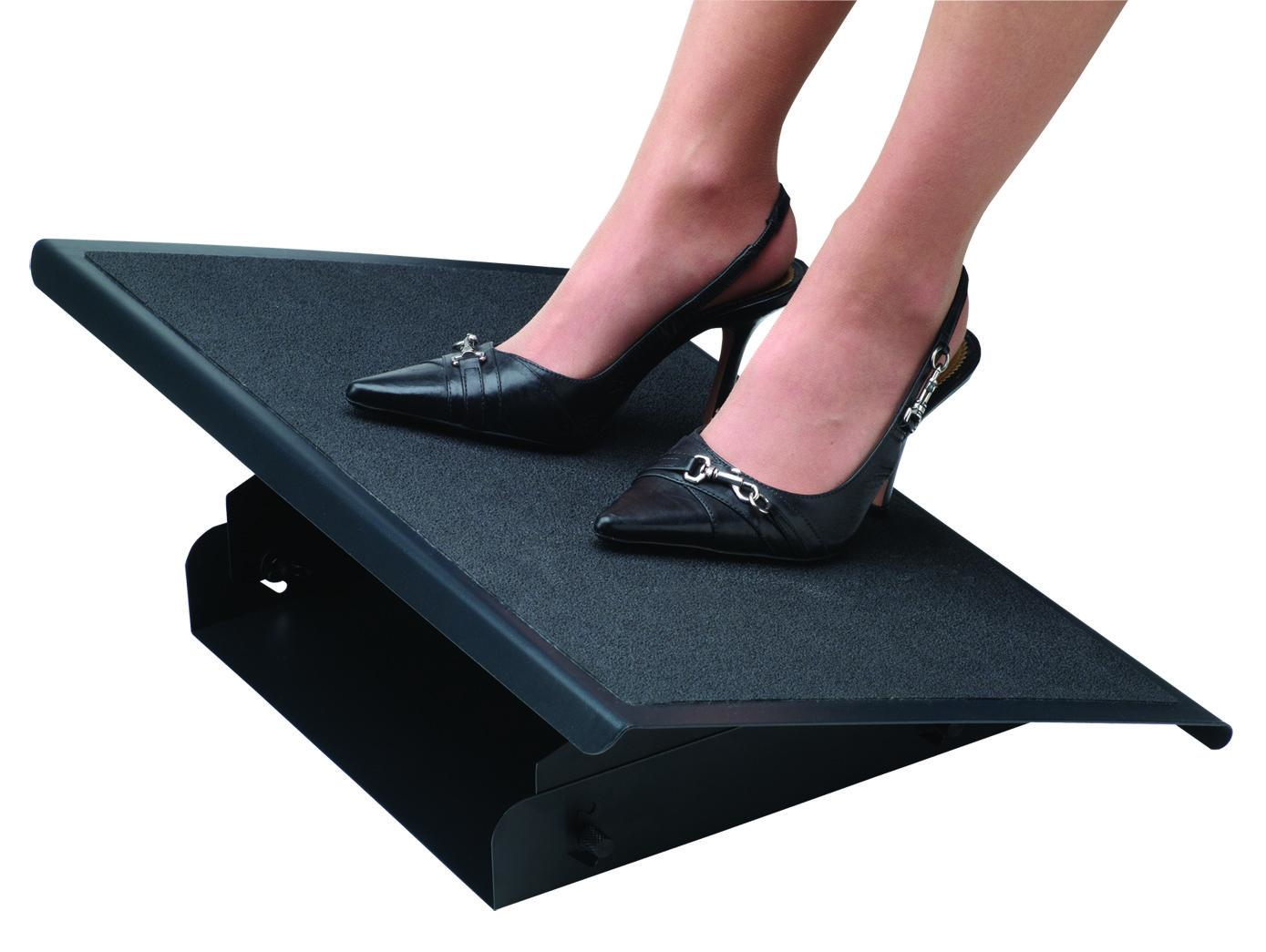Woman's feet wearing black heels are on a black footrest. The footrest is adjustable and has a textured surface.