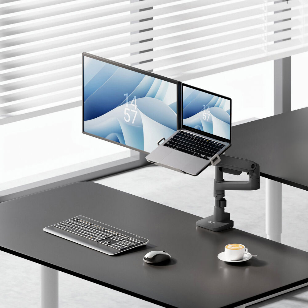 Desk setup: monitor and laptop on arm, keyboard, mouse, and coffee cup on a black desk. Window with blinds in background.
