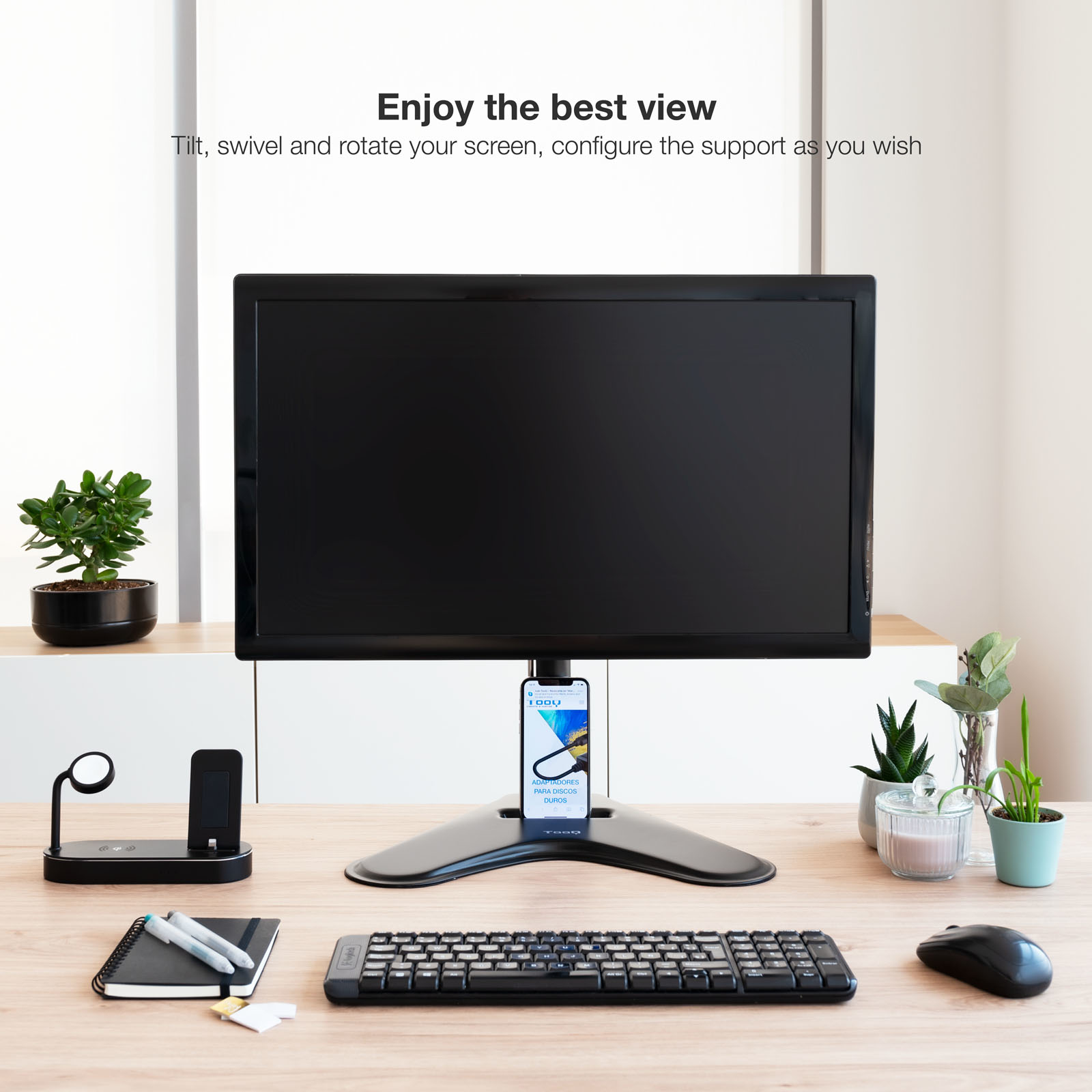 Monitor na statywie, z klawiaturą, myszą, roślinami i telefonem z reklamą. Tekst: Ciesz się najlepszym widokiem.