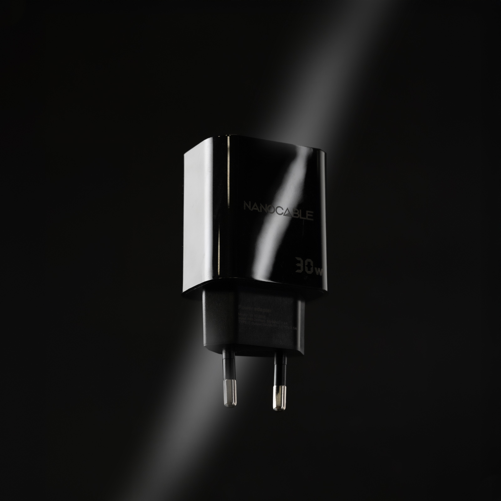 Ein schwarzes NANO CABLE Ladegerät mit 30W auf schwarzem Hintergrund. Weißes Licht scheint auf das Ladegerät.