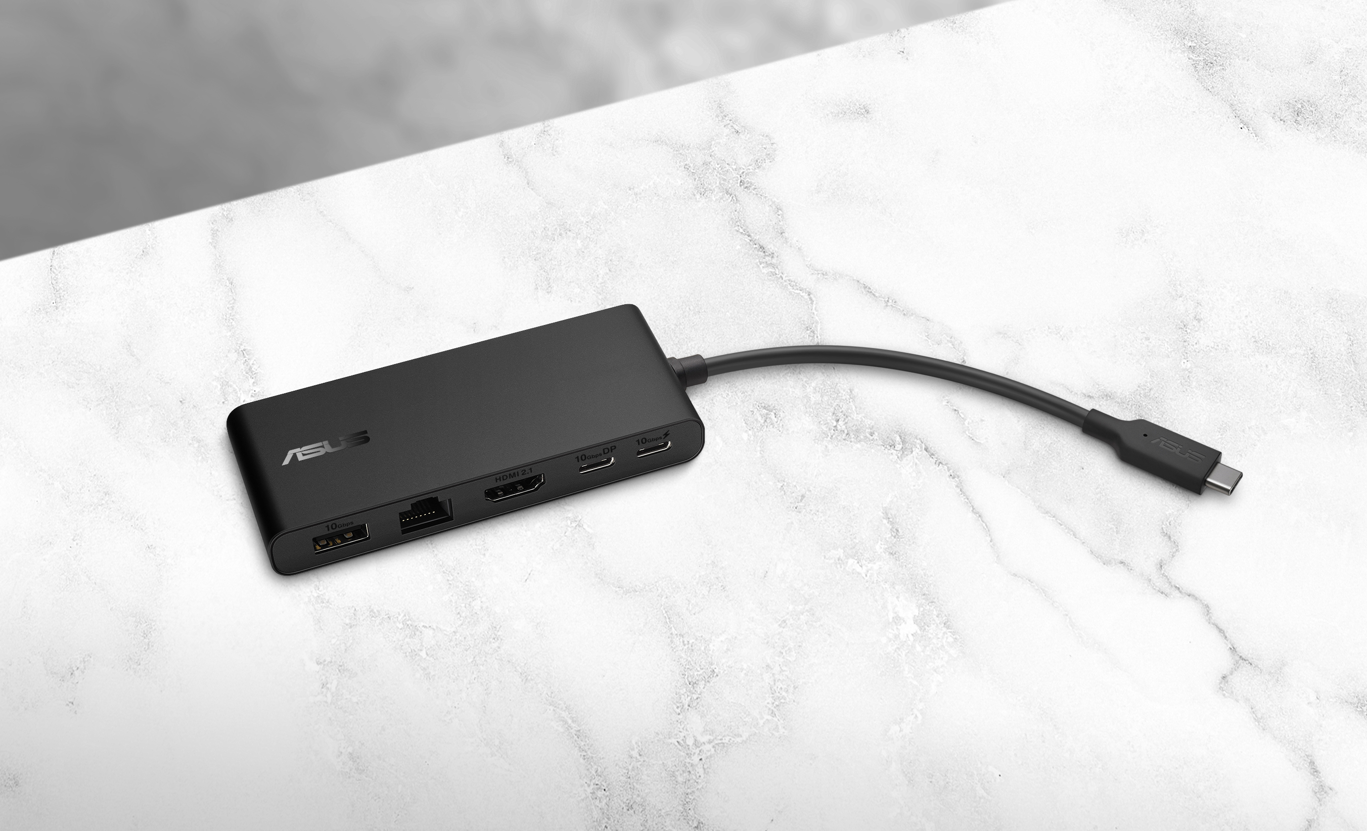 Black ASUS USB-C hub on a marble surface. It has multiple ports and a connected USB-C cable.