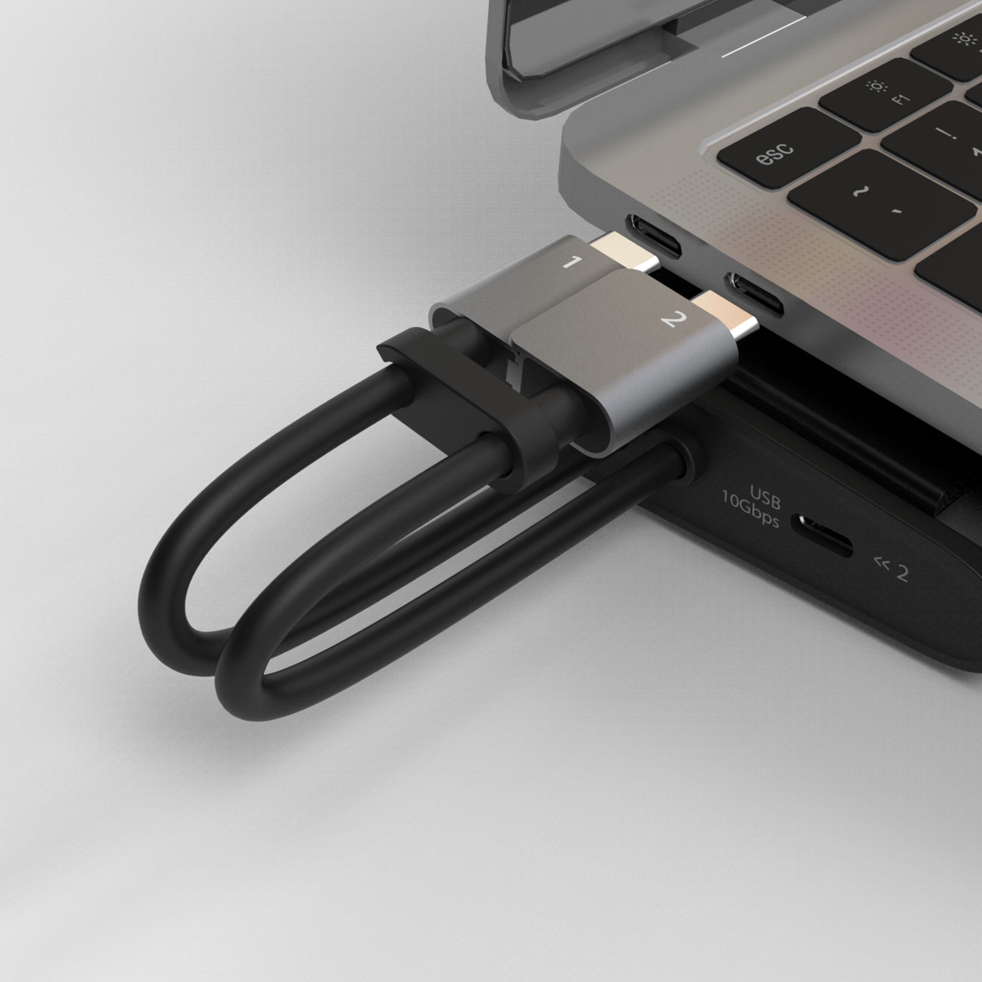 Un portátil está conectado a un concentrador USB negro a través de un adaptador plateado y cables negros. El fondo es blanco.
