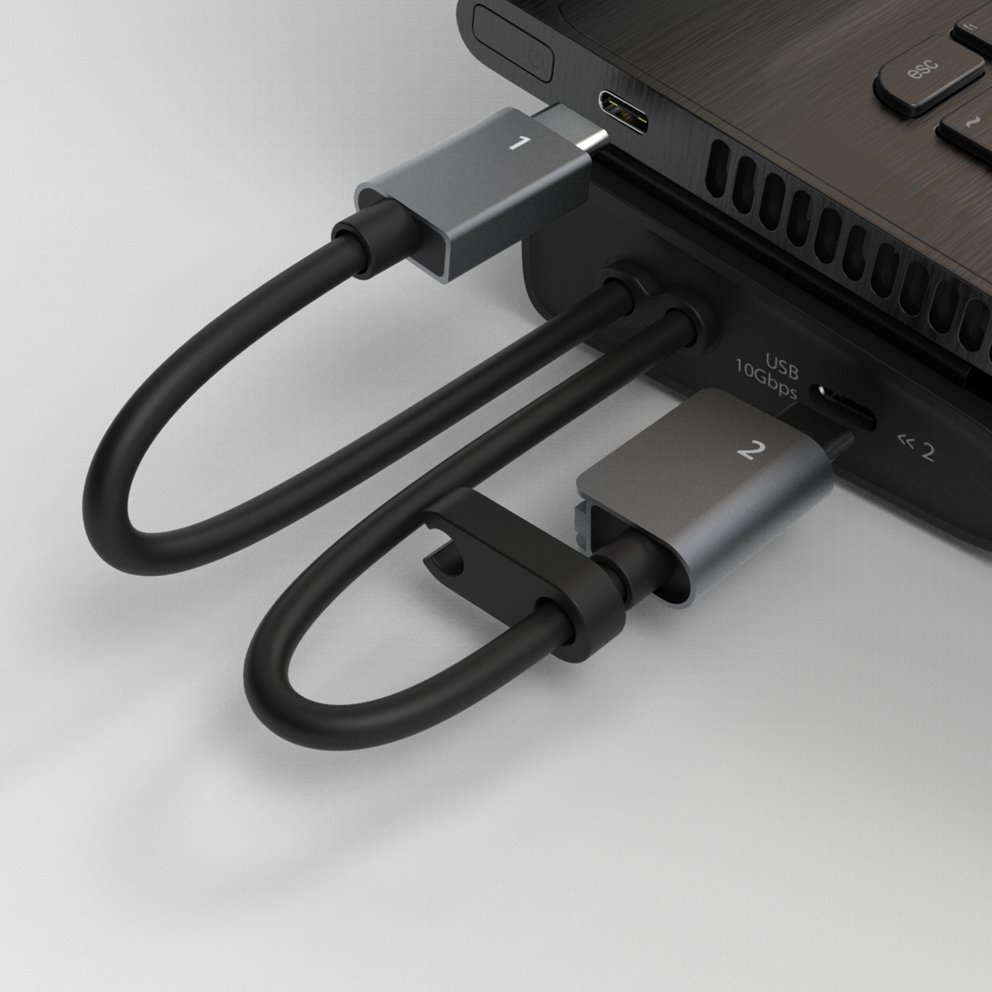 Un portátil con un concentrador USB conectado. Dos conectores USB-C plateados están conectados al portátil y al concentrador, con cables negros.