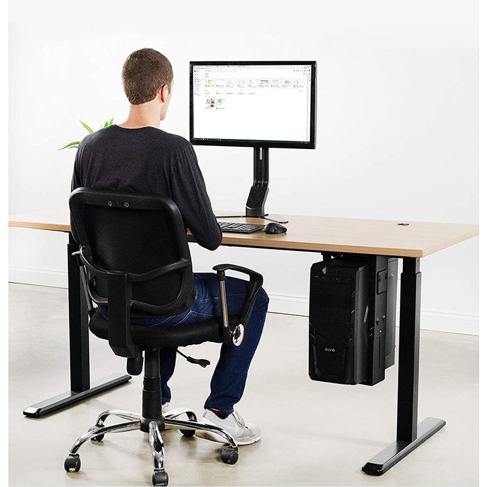 Ein Mann sitzt an einem Schreibtisch und blickt auf einen Computermonitor. Ein PC ist unter dem Schreibtisch montiert. Der Mann trägt Jeans und ein schwarzes Hemd.