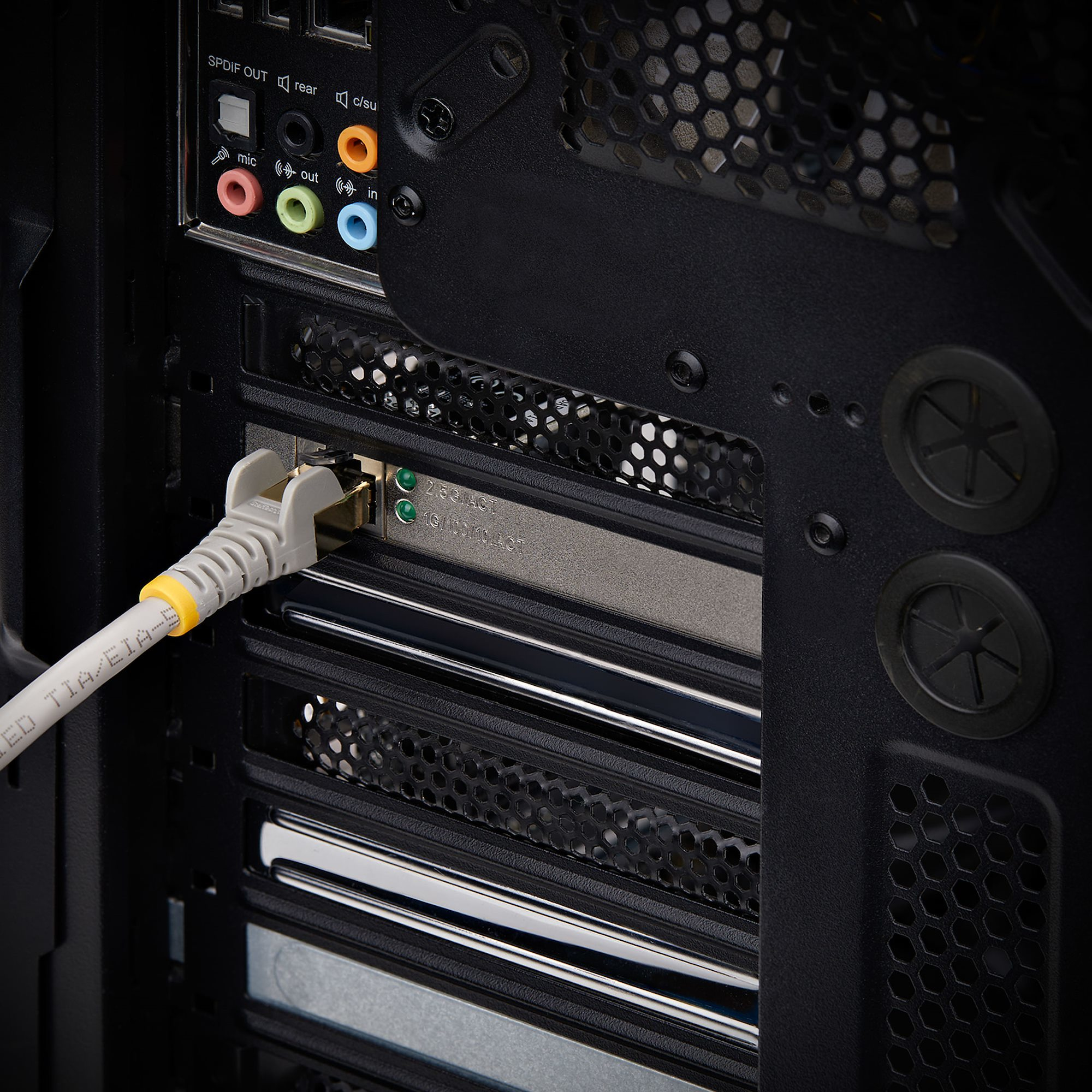 Die Rückseite eines Computers mit angeschlossenem Ethernet-Kabel ist abgebildet. Audioanschlüsse sind sichtbar. Das Gehäuse ist schwarz.