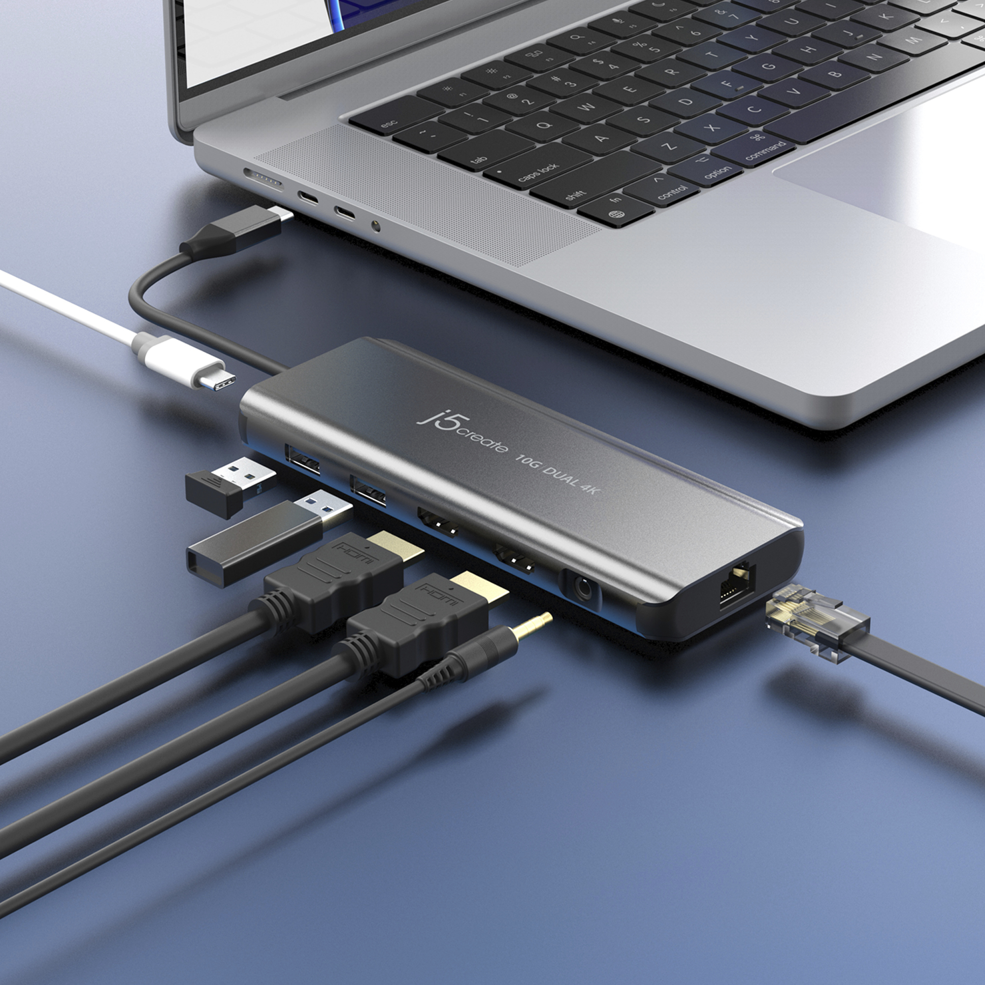 Laptop verbunden mit einem silbernen Hub mit HDMI-, USB- und Ethernet-Kabeln auf blauem Untergrund.