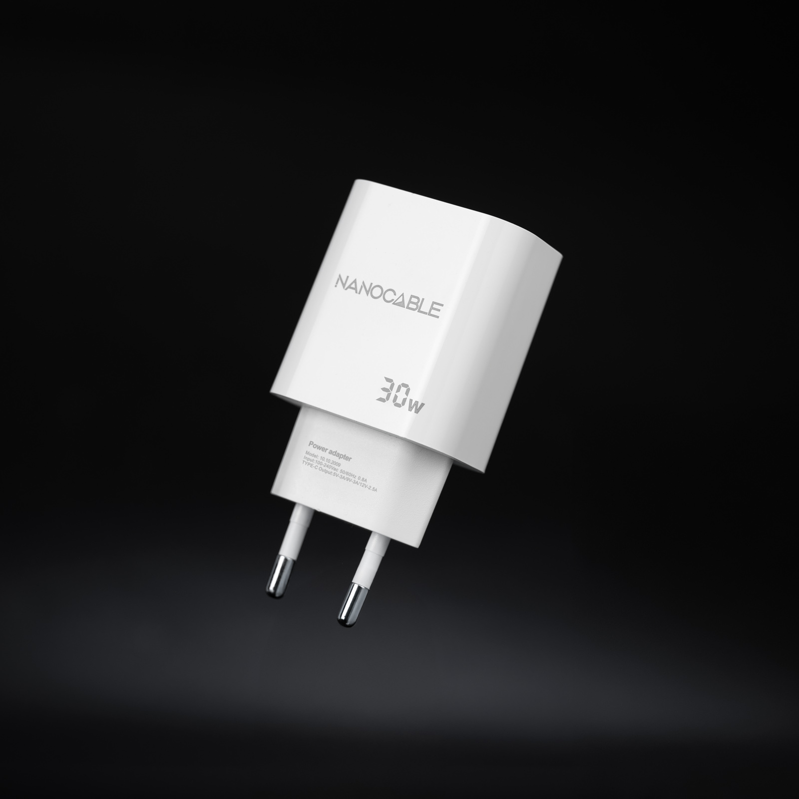 Weißes Nanocable 30W-Netzteil auf schwarzem Hintergrund. Es hat zwei Stifte und Produktinformationen.