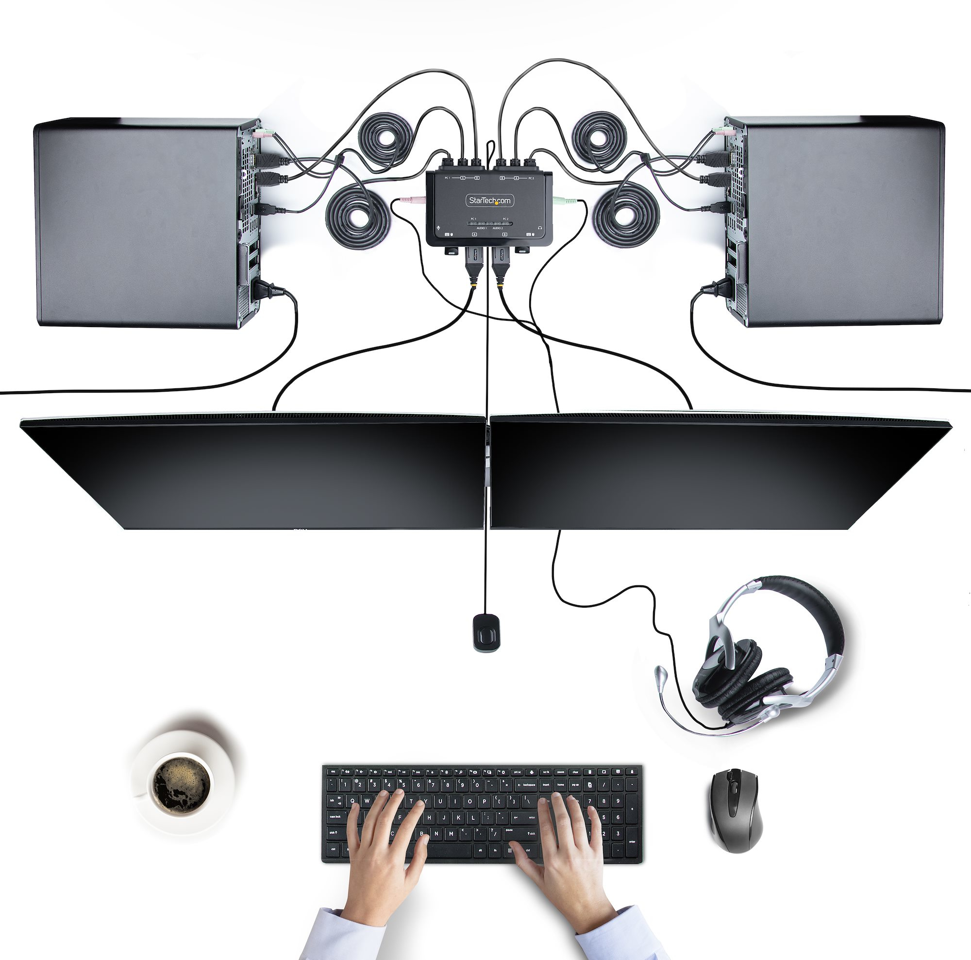 Draufsicht auf einen Arbeitsplatz mit zwei Computern, Monitoren, Tastatur, Maus, Kopfhörern und Kaffee.