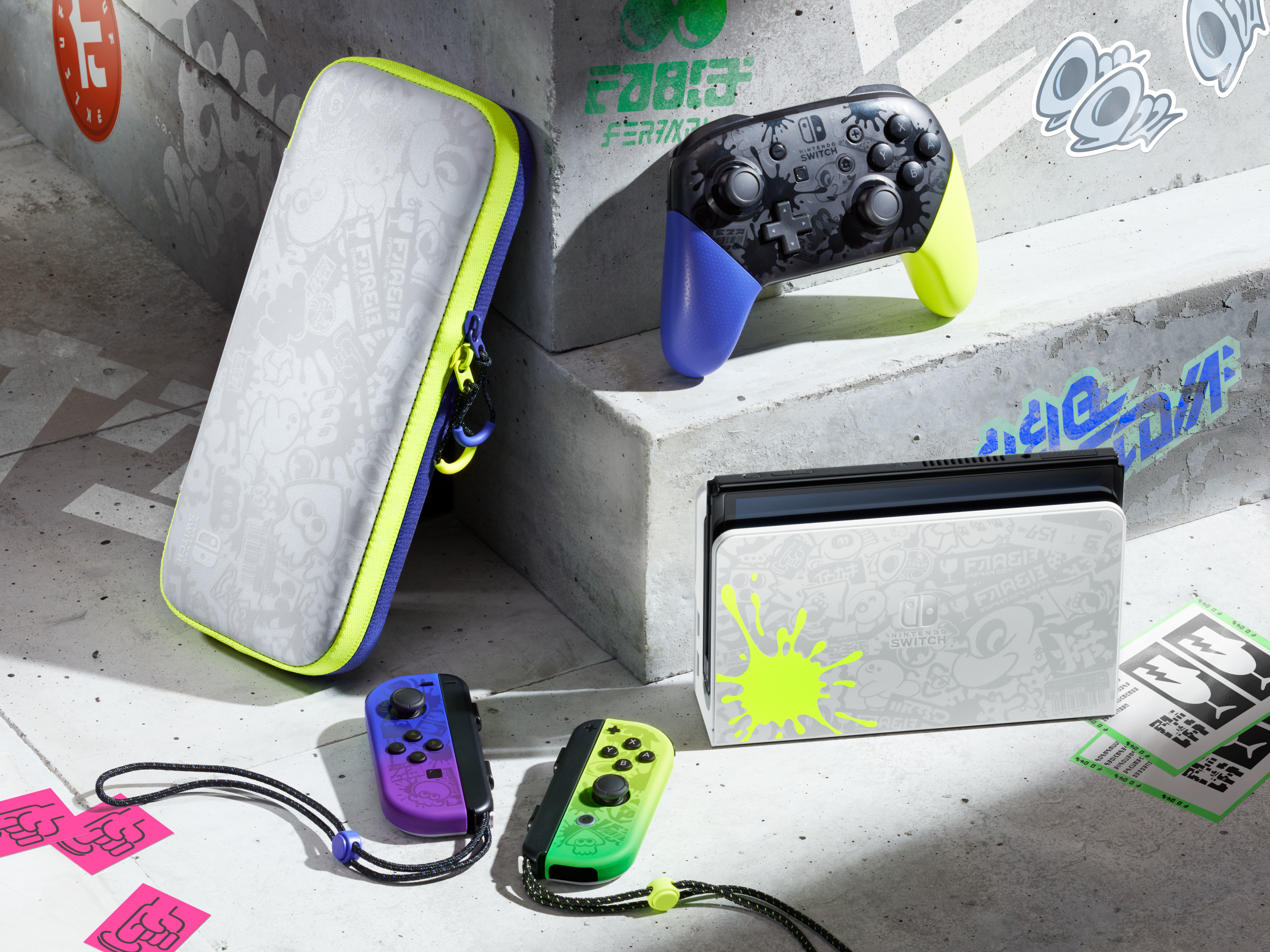 Imagen muestra accesorios Nintendo Switch en superficie de concreto. Incluye consola, mandos, funda y pegatinas.