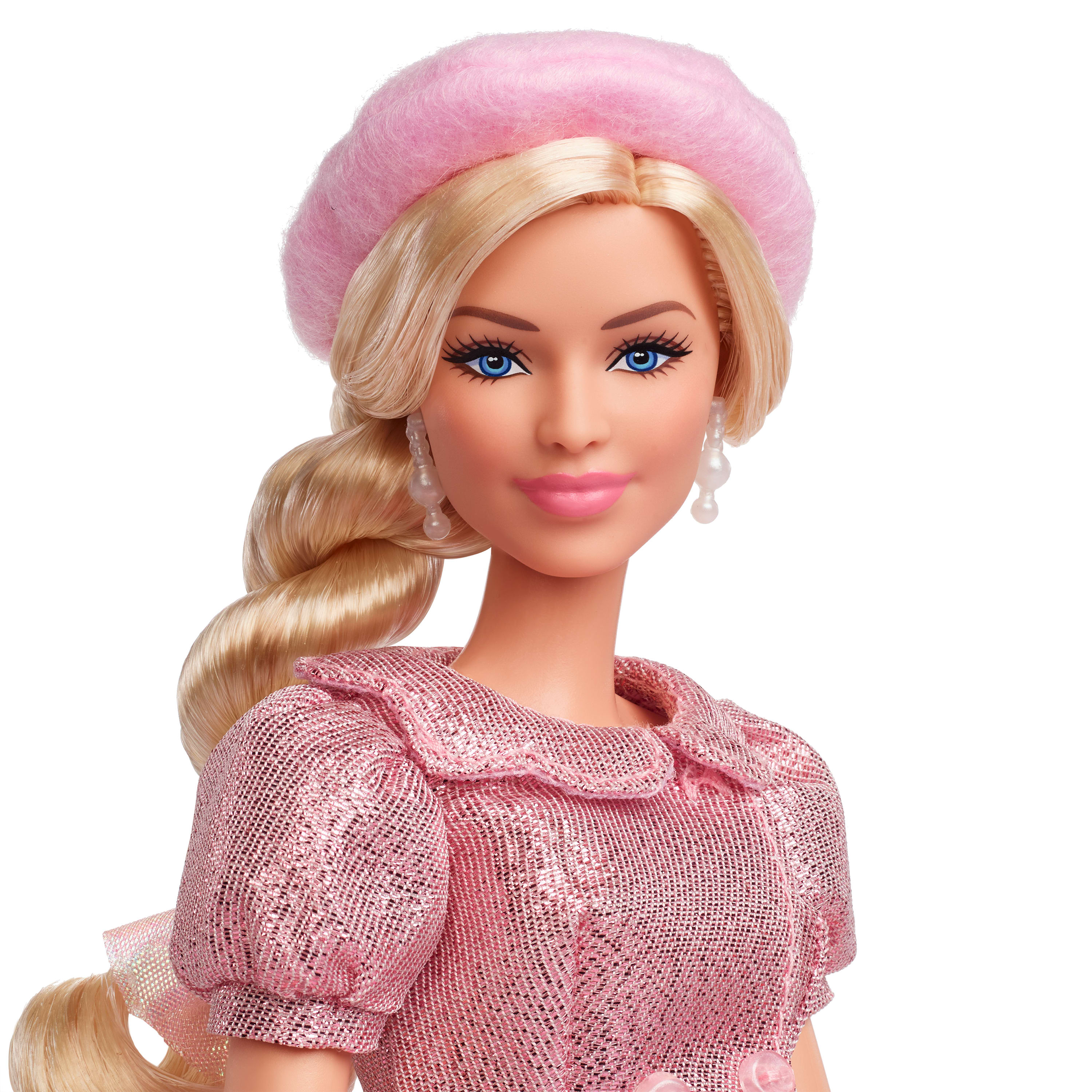 Una muñeca Barbie con cabello rubio, ojos azules y un atuendo rosa, incluyendo boina. Lleva aretes de perlas.