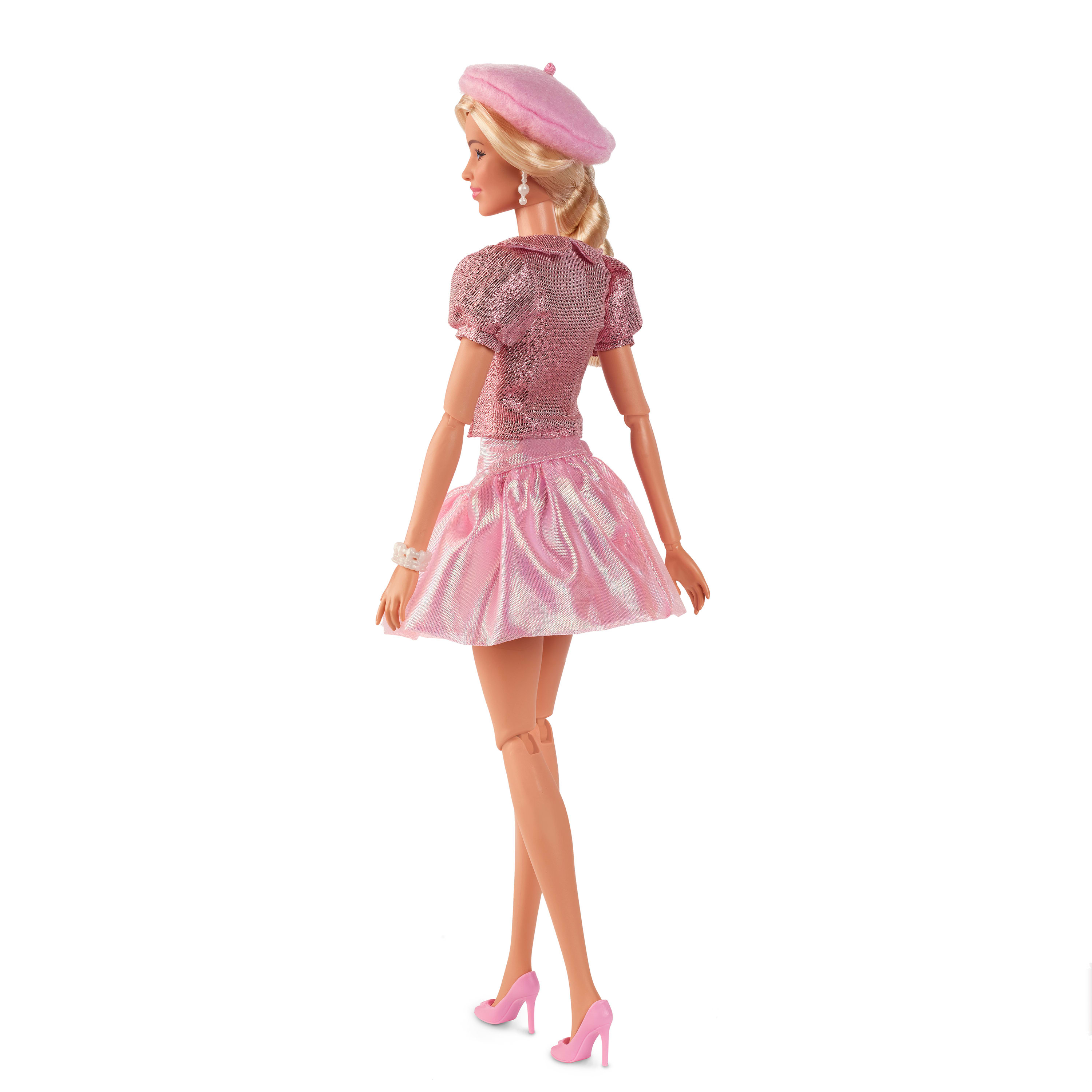 Una muñeca Barbie con atuendo rosa, boina y tacones, de espaldas a la cámara, sobre un fondo blanco.