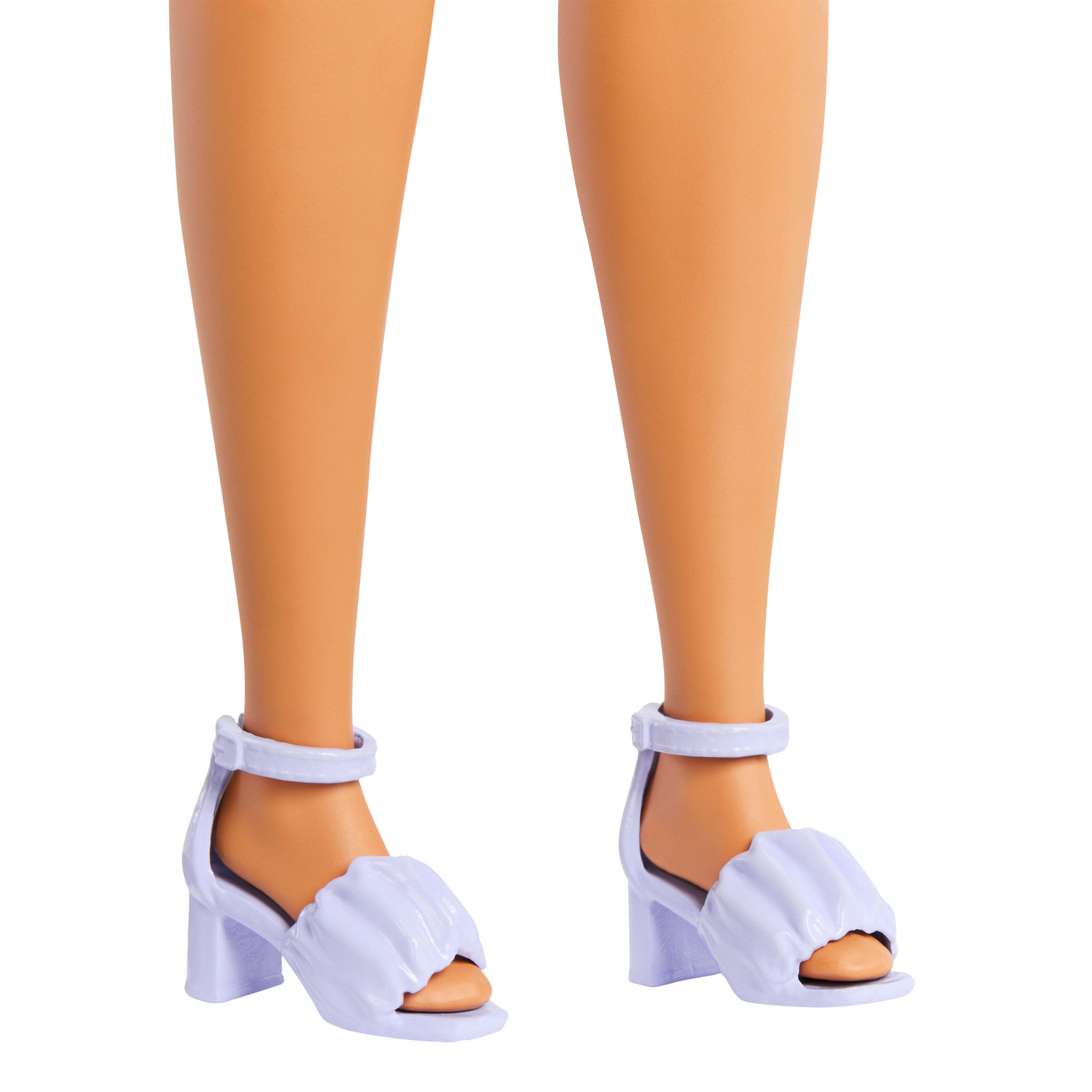 Beine und Füße einer Puppe mit hellvioletten Sandalen mit Riemen und gerüschtem Stoff über den Zehen. Der Hintergrund ist weiß.