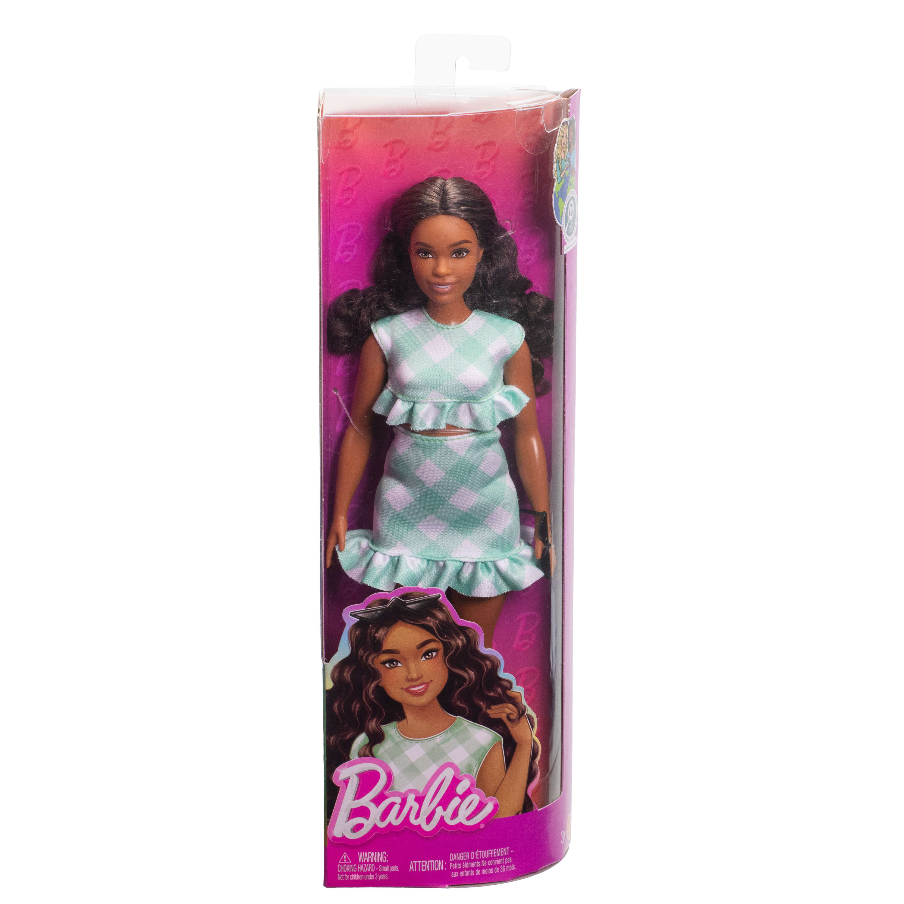 Barbie-Puppe in einer Box. Sie trägt ein kariertes Outfit. Die Box hat das Barbie-Logo. Der Hintergrund ist rosa.