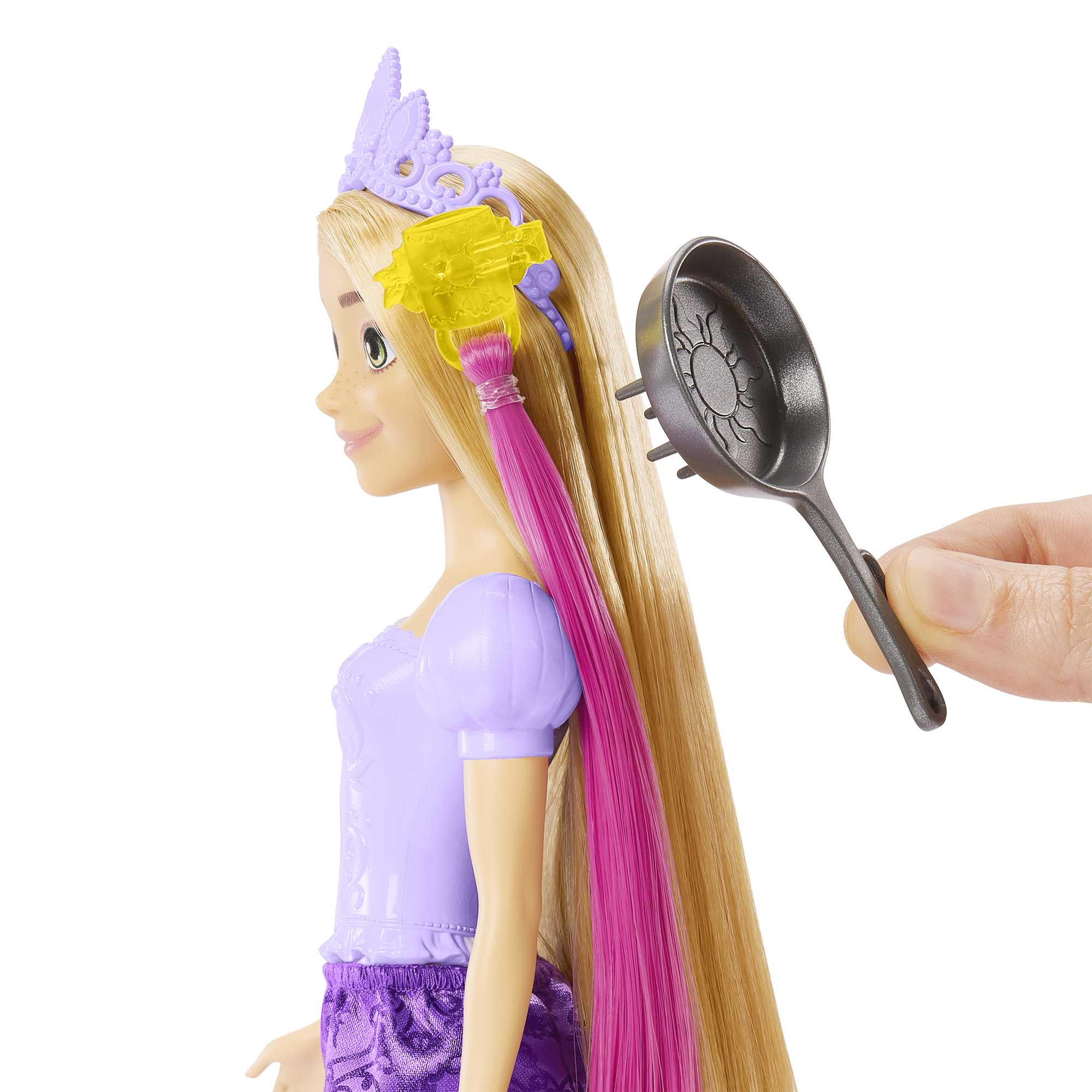 Eine Puppe mit blonden Haaren und einem lila Kleid. Eine Hand hält eine Pfanne in der Nähe der Haare der Puppe.