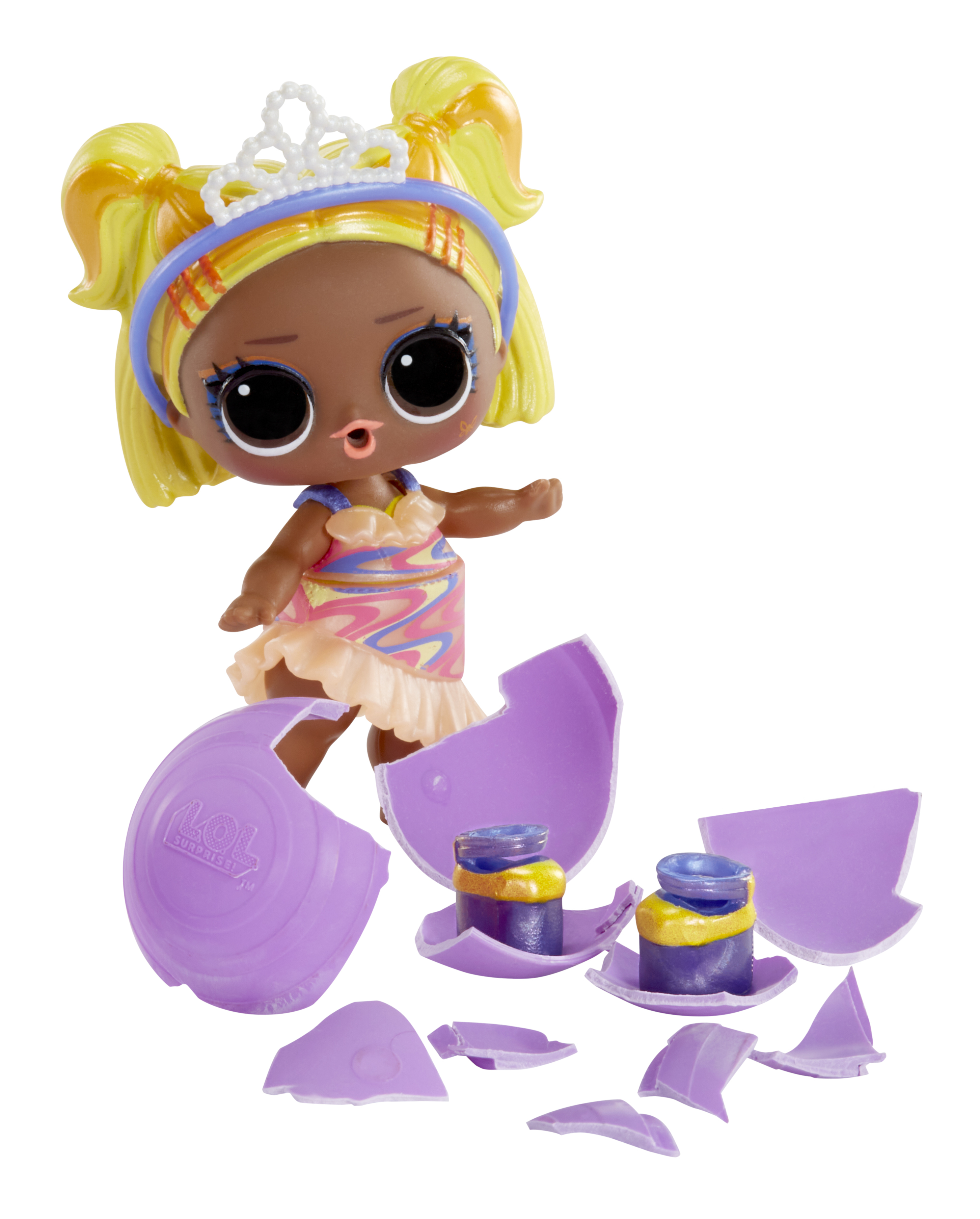 Lalka z żółtymi włosami i tiarą stoi obok zepsutej fioletowej zabawki. Widoczne są dwie małe butelki.