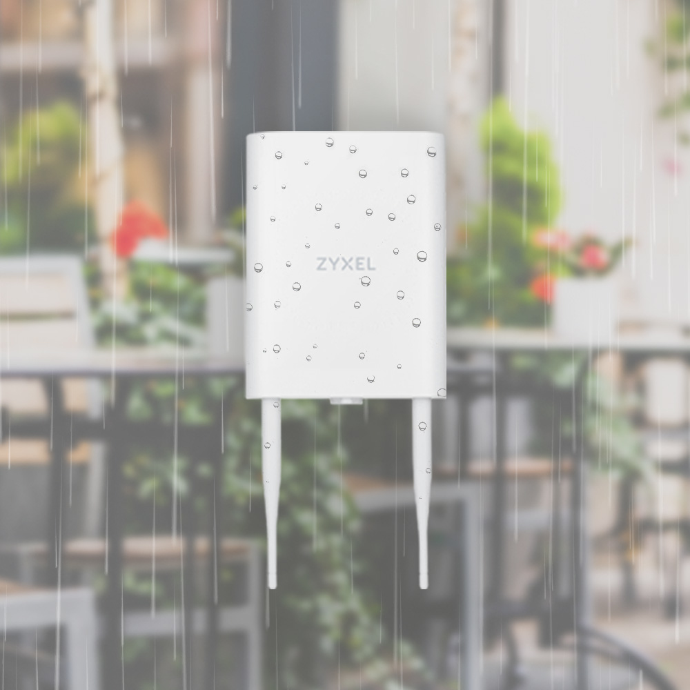 Biały router Zyxel z dwiema antenami pokazany w deszczu. Rozmyte tło, pokazujące otoczenie kawiarni.
