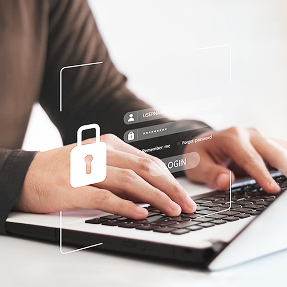 Osoba pisze na laptopie z interfejsem logowania. Ikona kłódki jest nałożona. Ekran pokazuje pola użytkownika, hasła i przycisk logowania.