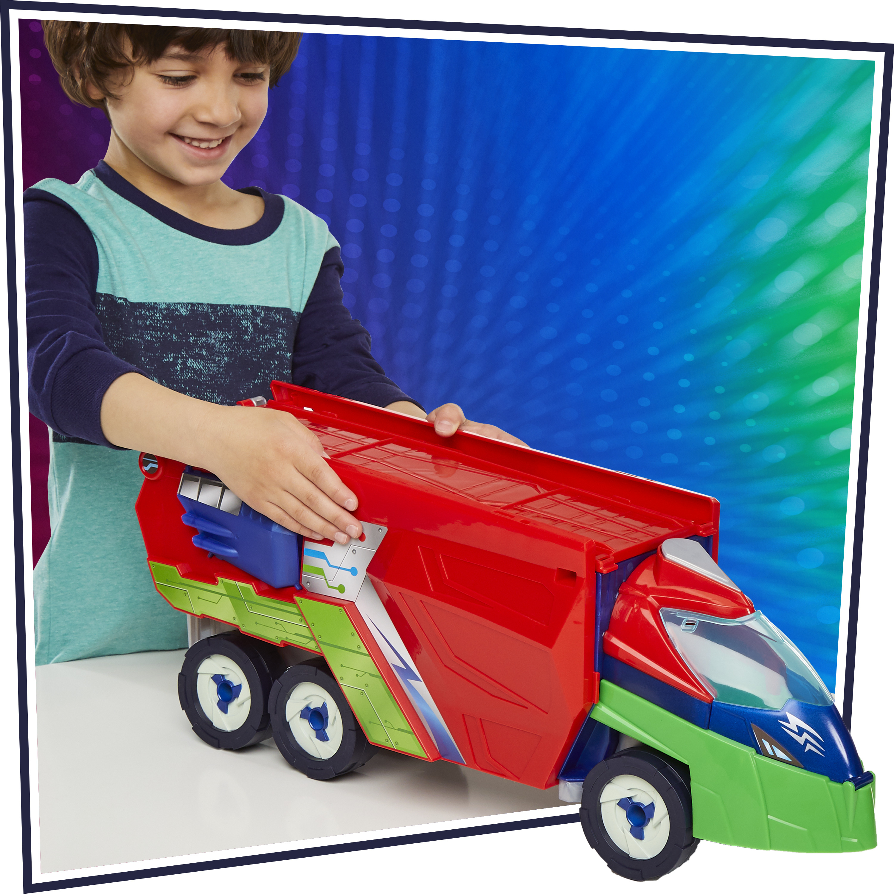 Un bambino sorride, gioca con un camion giocattolo rosso, verde e blu. Lo sfondo è sfumato blu e verde.