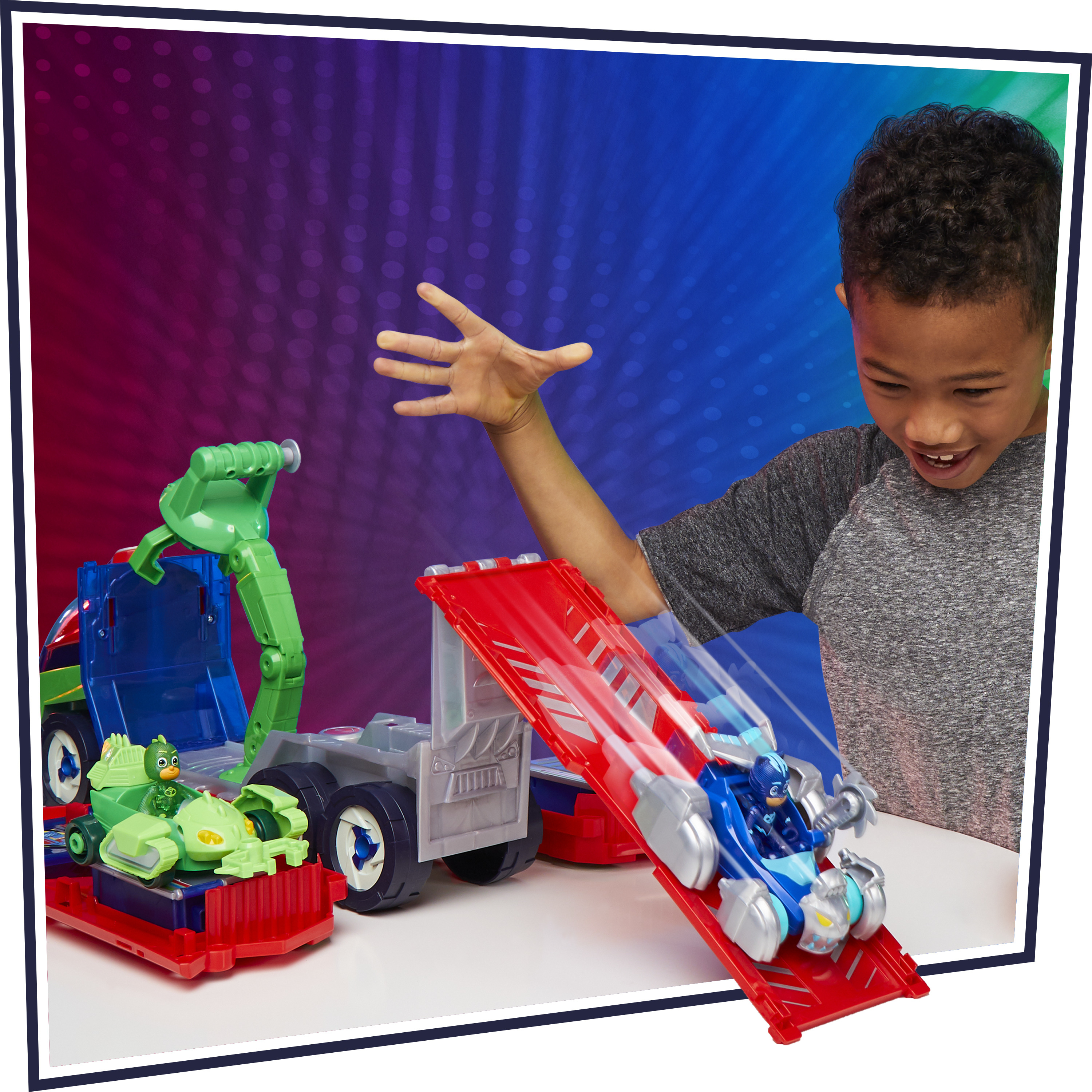 Un ragazzo gioca con le macchinine dei PJ Masks. Un'auto scende da una rampa. Lo sfondo è colorato.