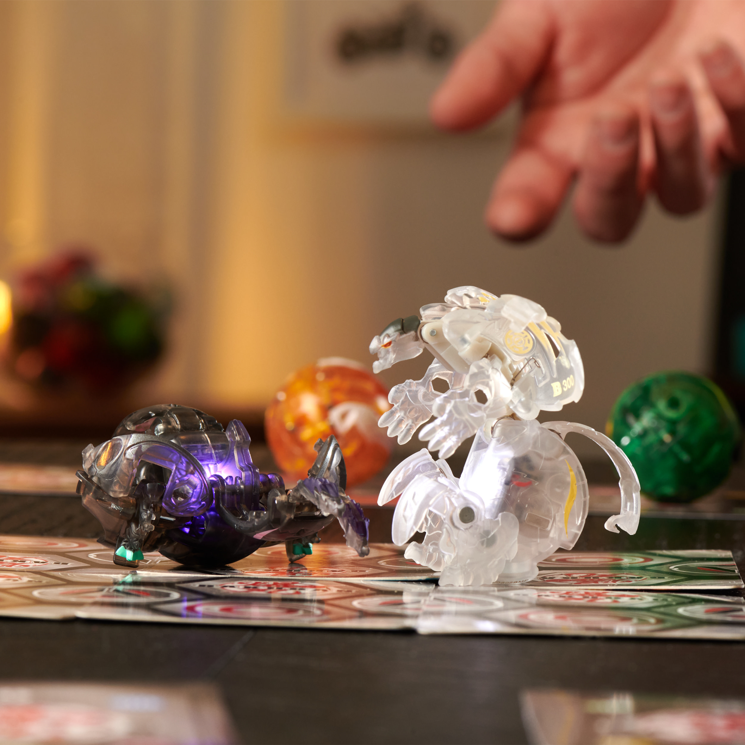 Dos figuras de juguete se enfrentan en un tablero de juego. Una mano se cierne sobre ellas. Otras piezas de juego están en el fondo.