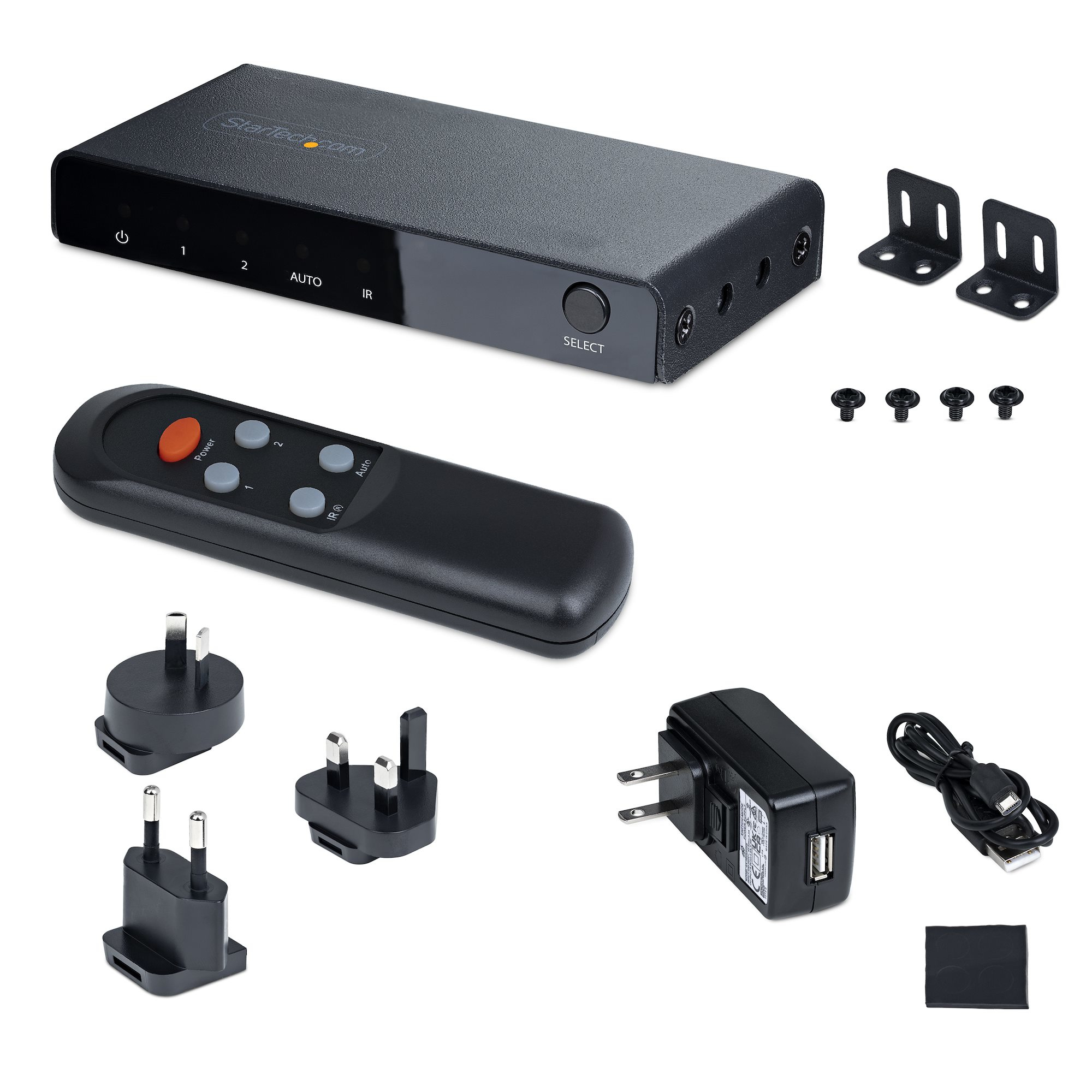 Dispositivo negro con accesorios: mando, enchufes, adaptador, tornillos y soportes. Incluye cable USB y almohadilla negra.