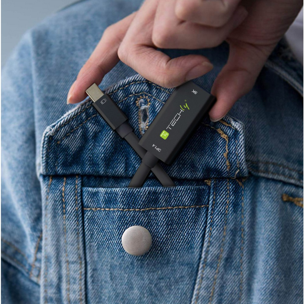 Una mano sostiene un adaptador Techly negro y un cable USB-C. El adaptador está en el bolsillo de una chaqueta vaquera.