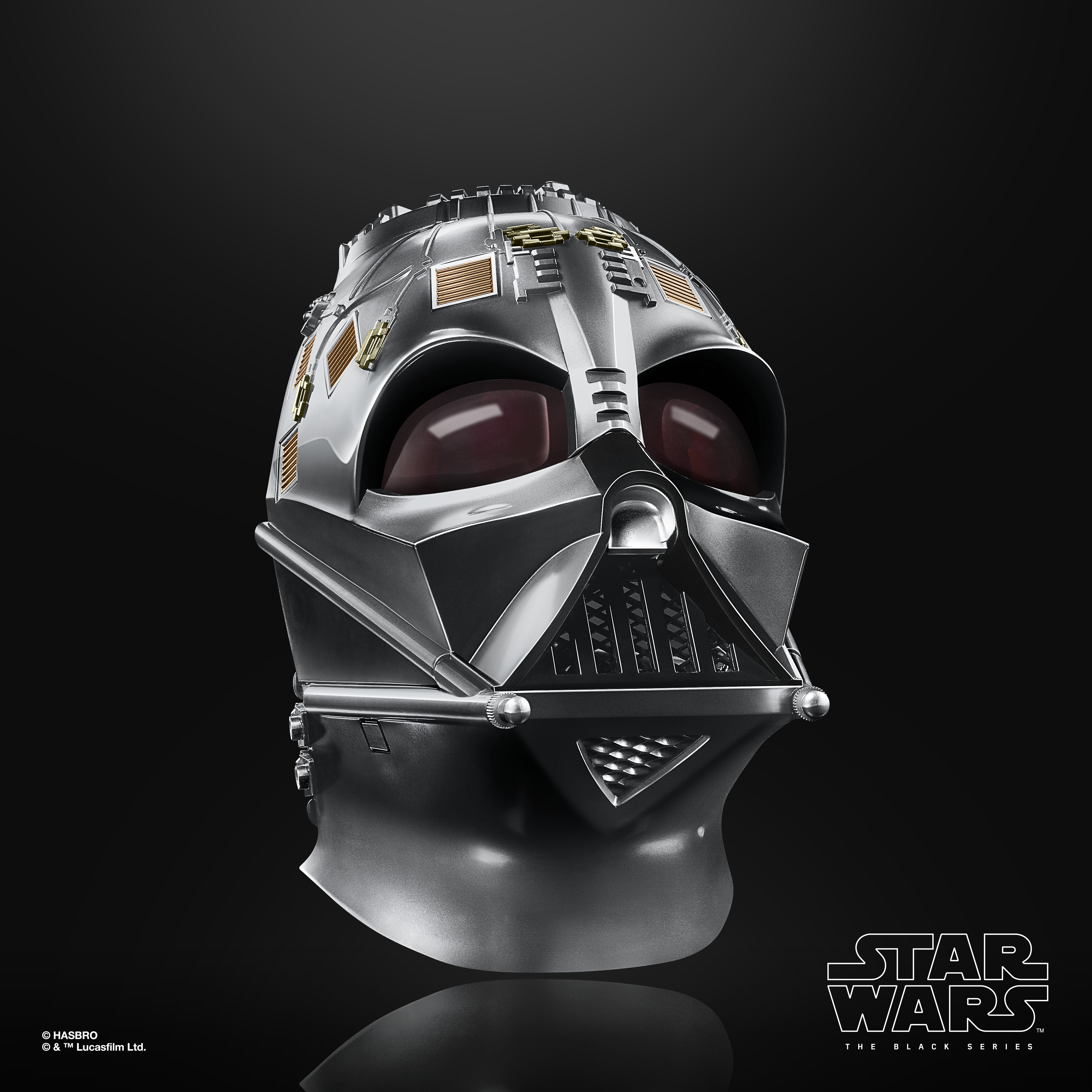 Primo piano di un elmetto di Darth Vader, argento metallizzato con lenti rosse. Poggia su una superficie nera riflettente.