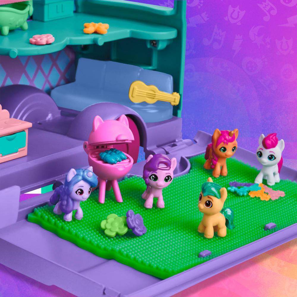 Un juego de juguetes presenta figuras de pony alrededor de una parrilla. Un sofá y una guitarra están en el fondo. La escena es colorida con morado, verde y rosa.