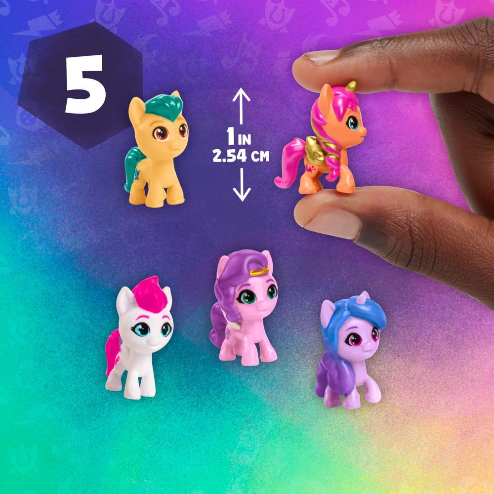 Se muestran cinco figuras coloridas de My Little Pony. Una la sostiene una mano. Hay un indicador de tamaño. El fondo es morado con formas.