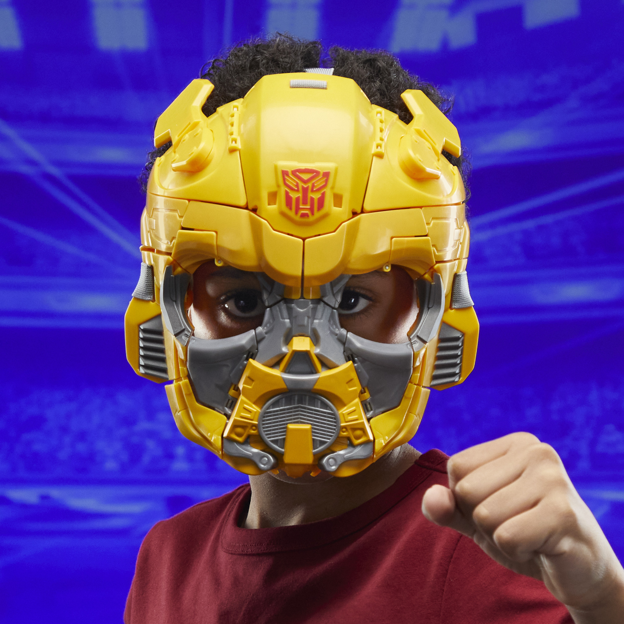 Un niño con un casco amarillo de Bumblebee, apretando el puño. El fondo es azul.
