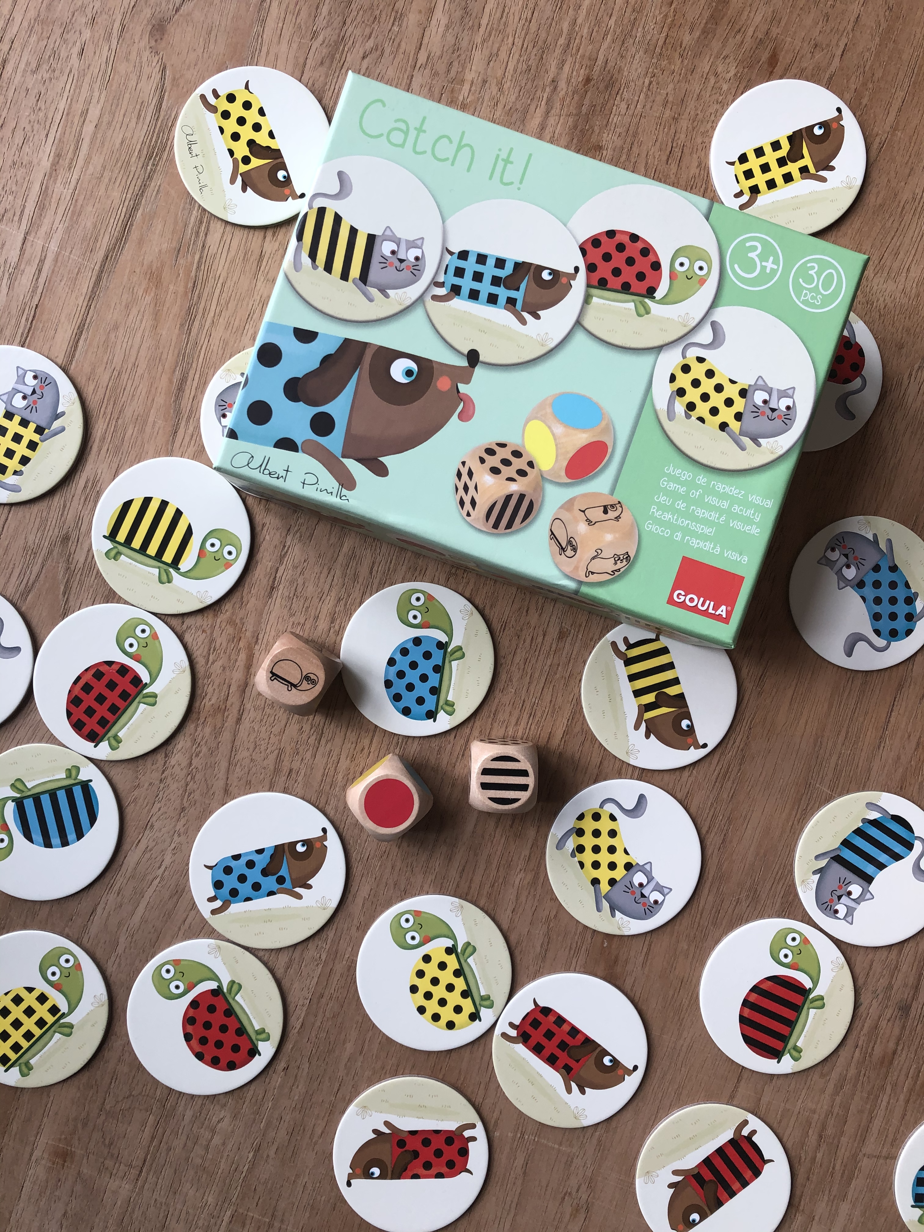 Pudełko z grą z ilustracjami zwierząt i elementami gry rozrzuconymi na drewnianej powierzchni.