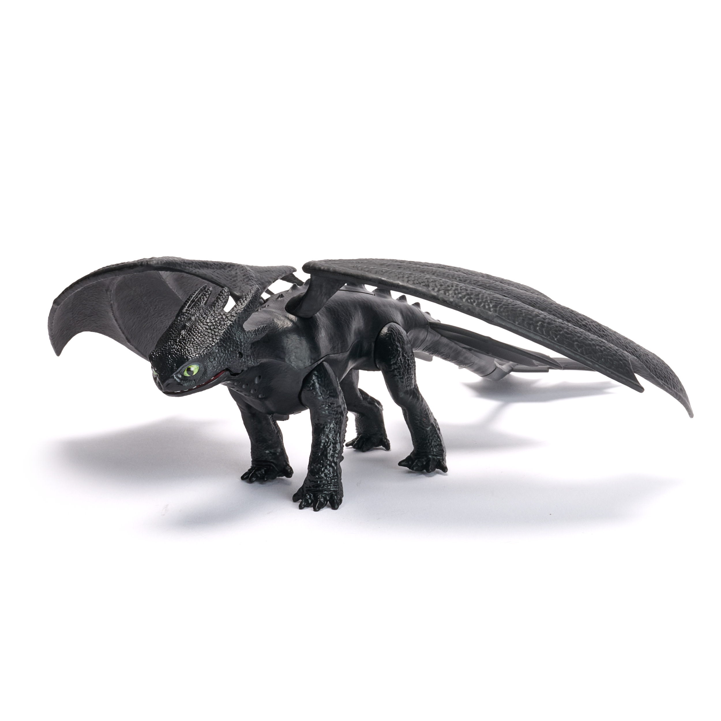 Un juguete de dragón negro con ojos verdes y alas grandes sobre una superficie blanca.