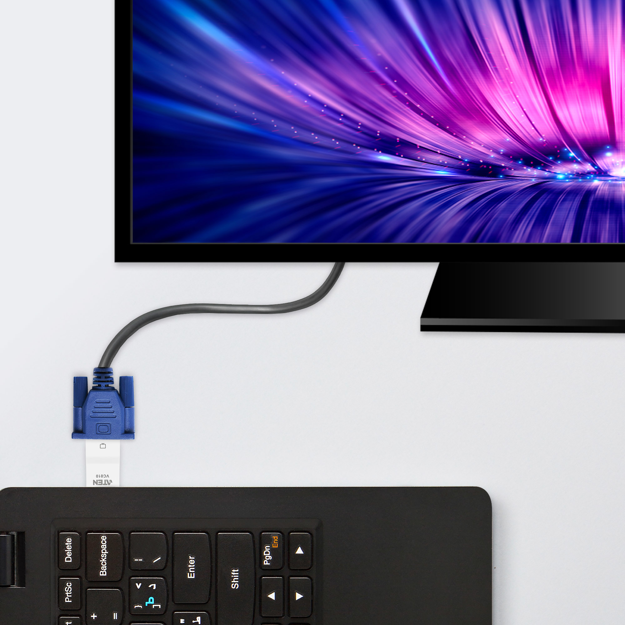Ein Computermonitor zeigt ein blaues und violettes Lichtmuster. Eine Tastatur und ein blaues VGA-Kabel sind im Vordergrund.