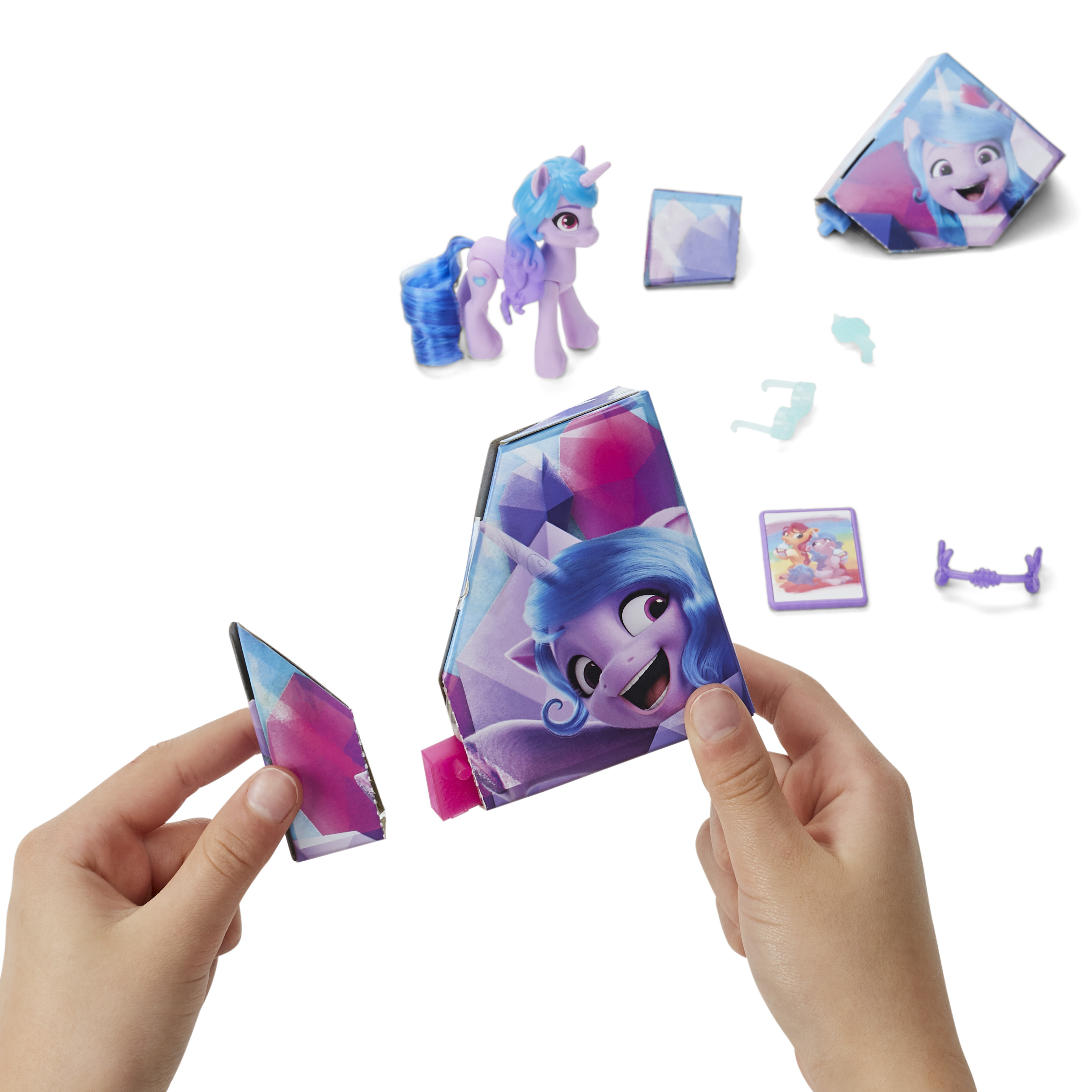 Un set di giocattoli My Little Pony con un personaggio pony, accessori e una scatola aperta con le mani.