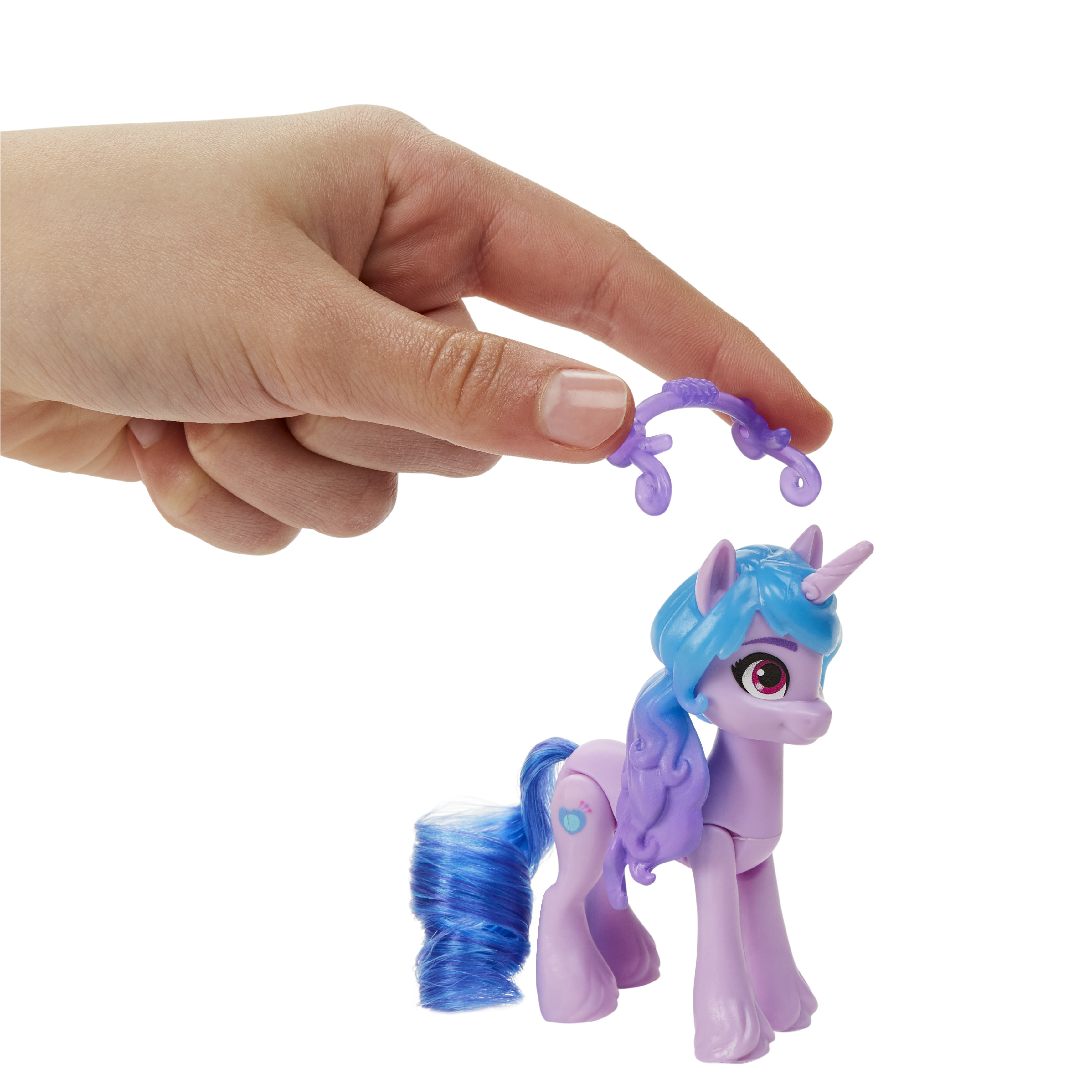 Una mano tiene un accessorio viola sopra un pony giocattolo. Il pony è viola con i capelli blu, un corno e sfondo bianco.