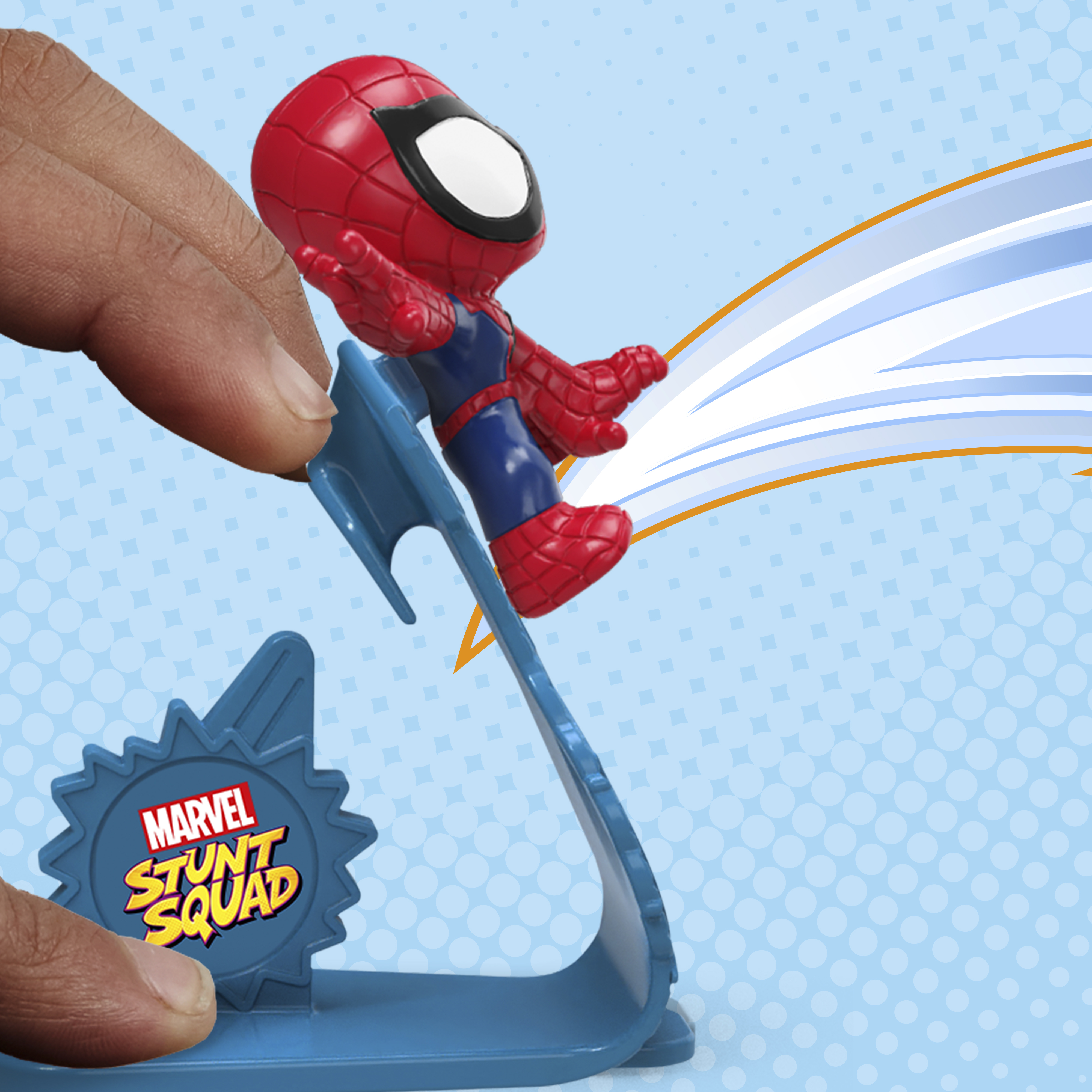 Un juguete de Spider-Man se lanza desde una rampa de acrobacias azul. Una mano sostiene el juguete. Fondo azul y blanco.