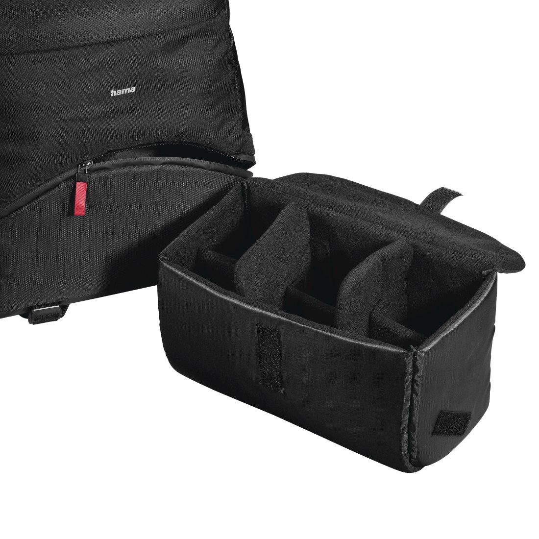 Czarna torba na aparat Hama, częściowo otwarta, odsłaniająca przegródki. Czerwony zamek błyskawiczny i detale zapięcia na rzep. Tło jest białe.