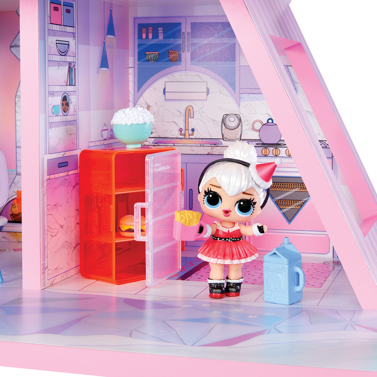 Lalka w czerwonej sukience i czapce Mikołaja stoi w różowej kuchni domku dla lalek. Jest lodówka, popcorn i karton mleka.