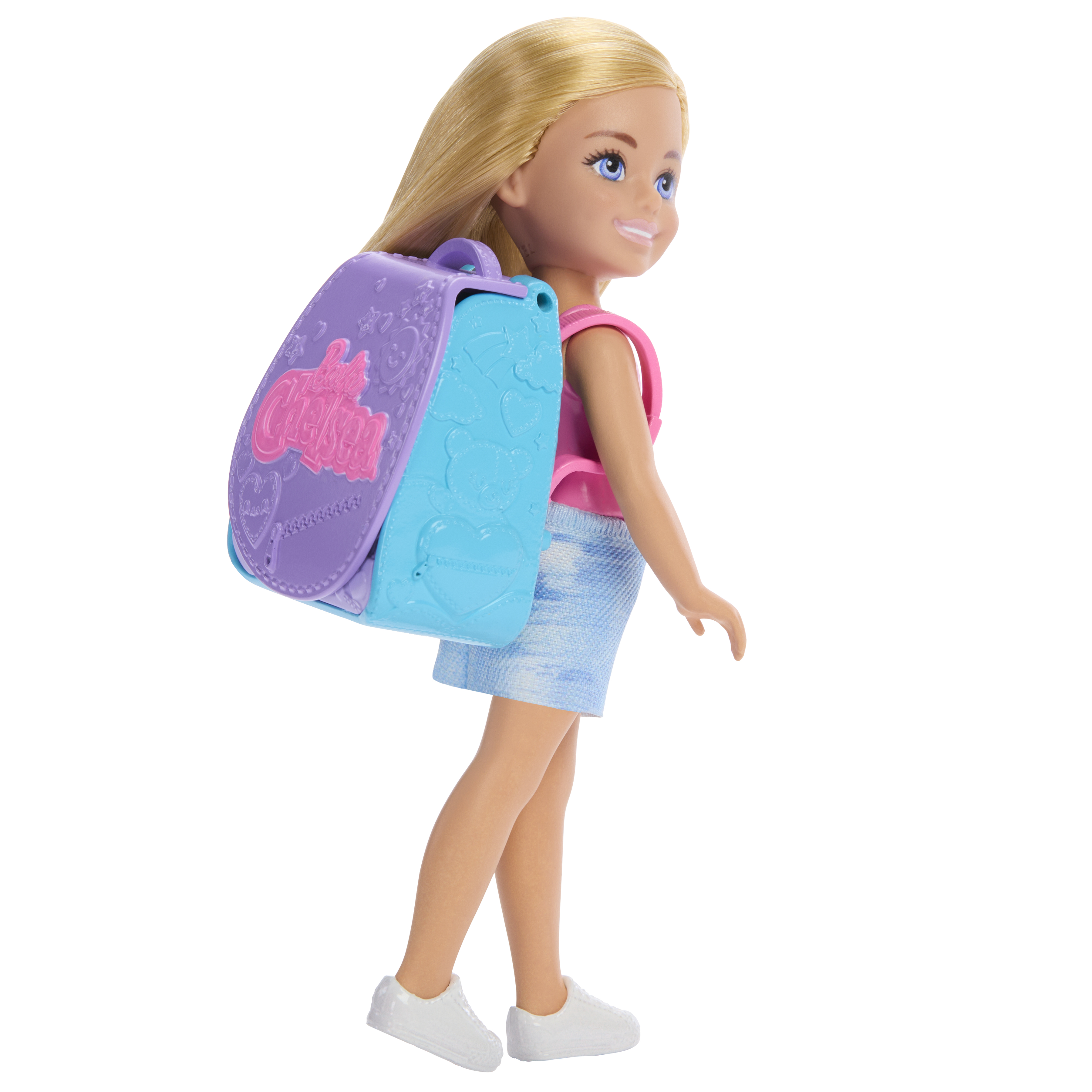 Eine Puppe mit blonden Haaren, die ein rosa Oberteil, einen Jeansrock und weiße Schuhe trägt. Sie trägt einen lila-blauen Rucksack.