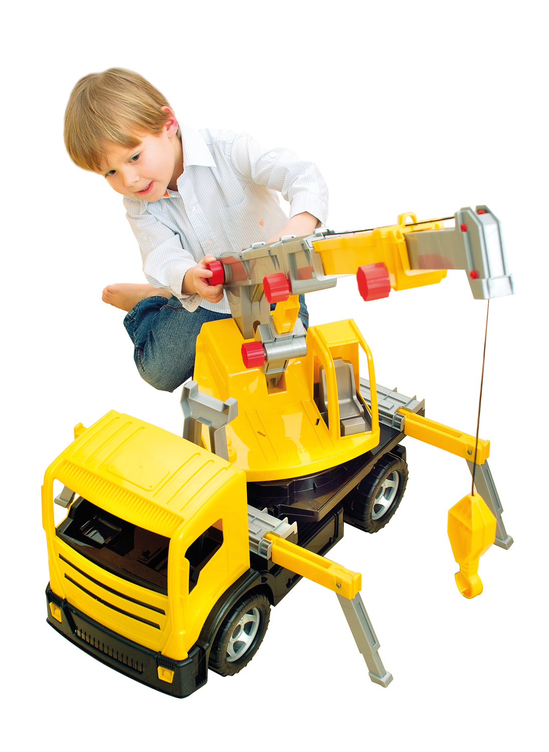 Un bambino gioca con un camion gru giocattolo giallo. La gru ha un gancio e il bambino tocca la gru con le mani.