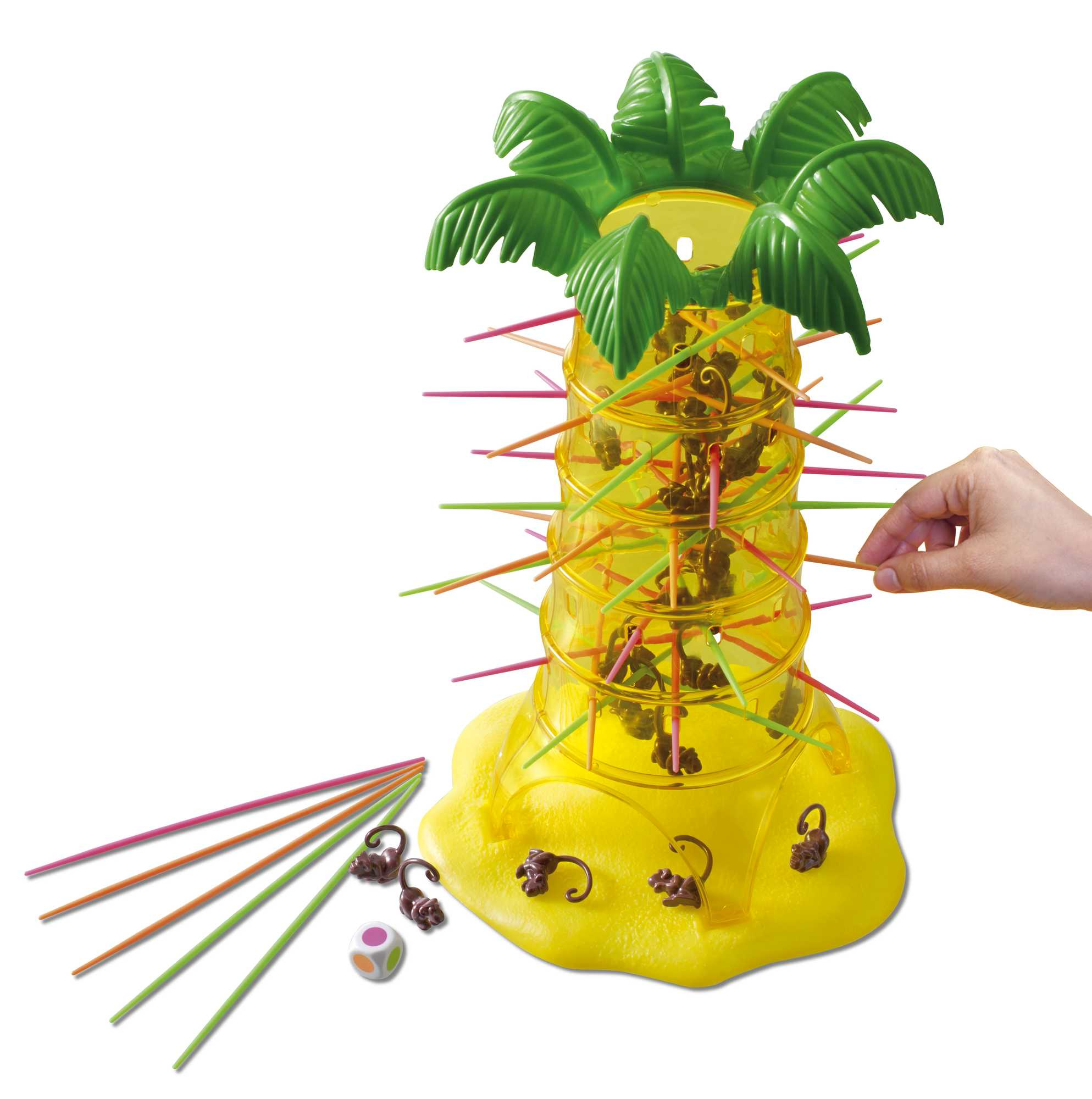 Gra o tematyce małp. Konstrukcja w kształcie palmy trzyma małpy. Ręka wyjmuje patyk. Patyki, małpy i kostka leżą na stole.