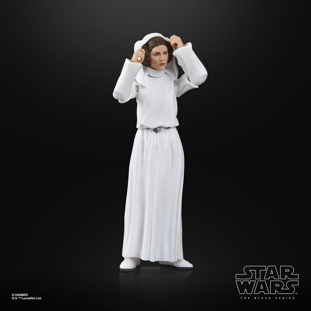 Beyaz elbiseli, kapüşonlu, elleri başının yanında Prenses Leia figürü. Siyah arka plan ve Star Wars logosu.